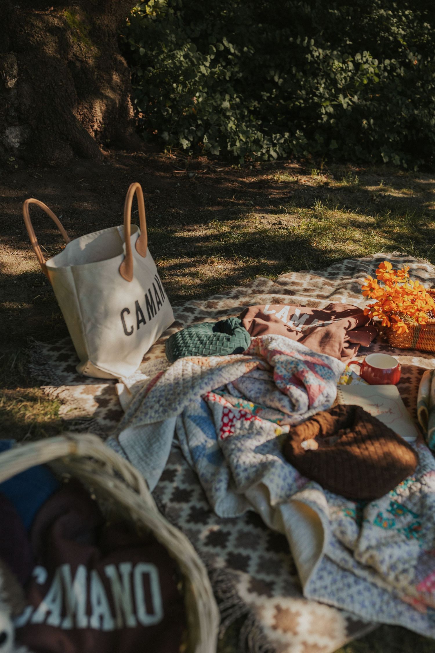 Collection of clothing and textiles spread out near a white canvas bag outdoors.