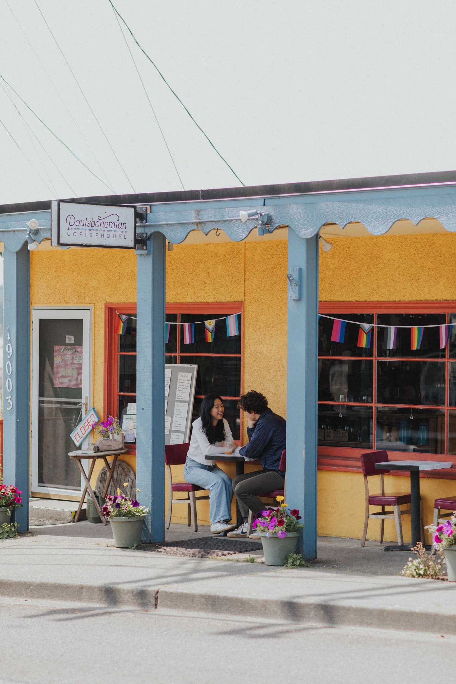 Yellow storefront with blue trim and outdoor seating area.