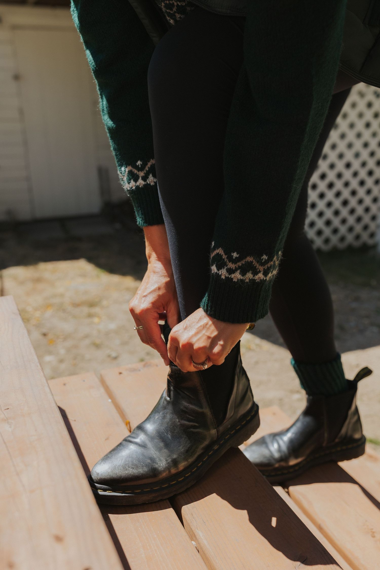 Close-up shots of black leather boots being put on wooden deck steps.