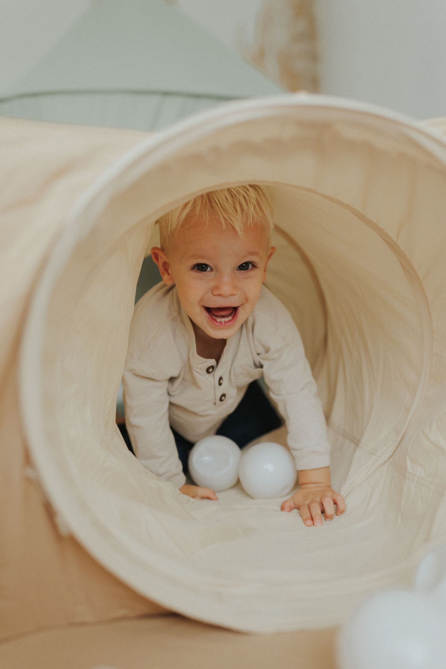 A playful scene with white balls and a fabric tunnel creating an indoor play space.