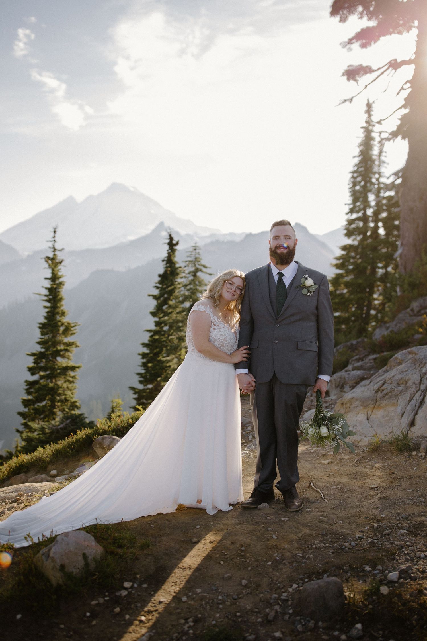 Wedding portrait session on mountain ridge with dramatic mountain peaks in background.