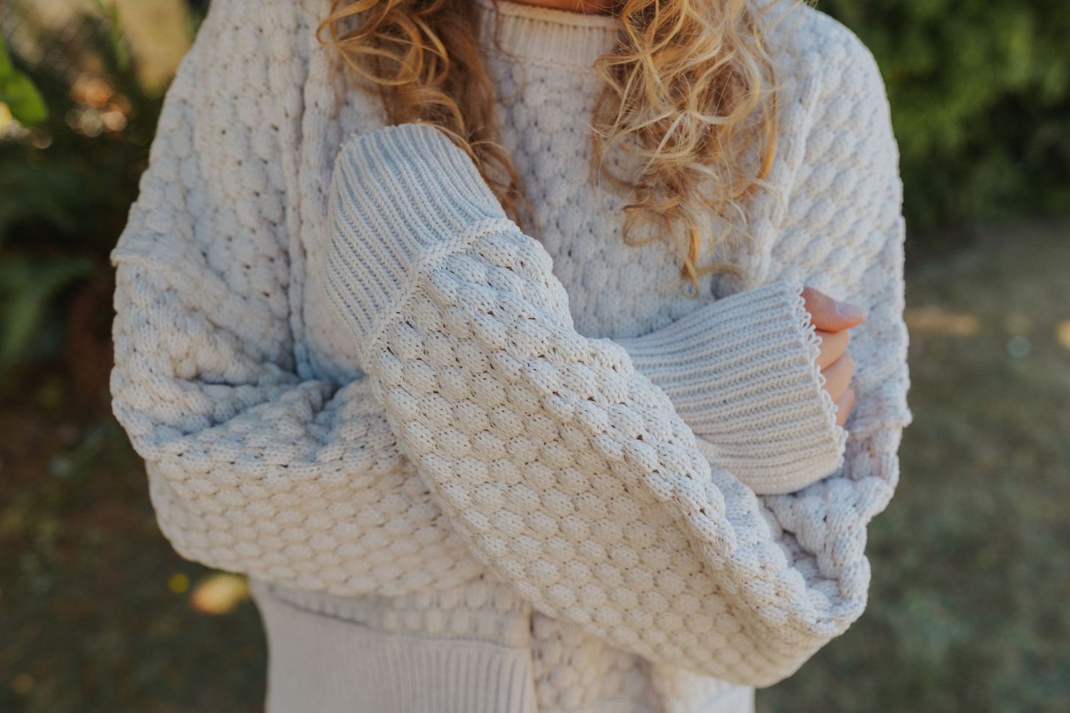 Close-up shots of a cozy white knit sweater with textured pattern details.