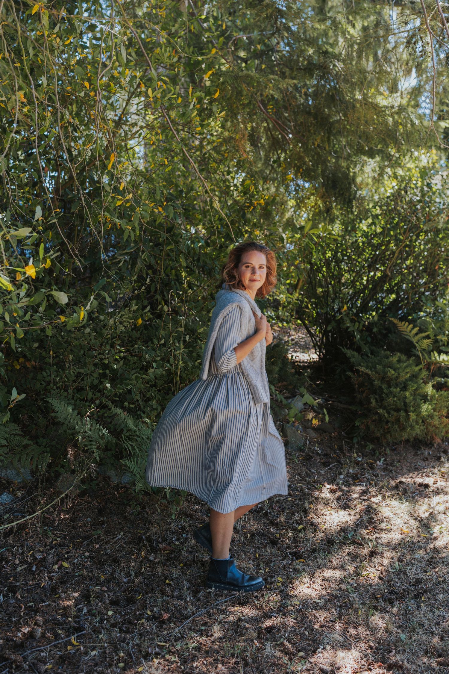 A playful outdoor photoshoot with someone posing against lush greenery in natural lighting.