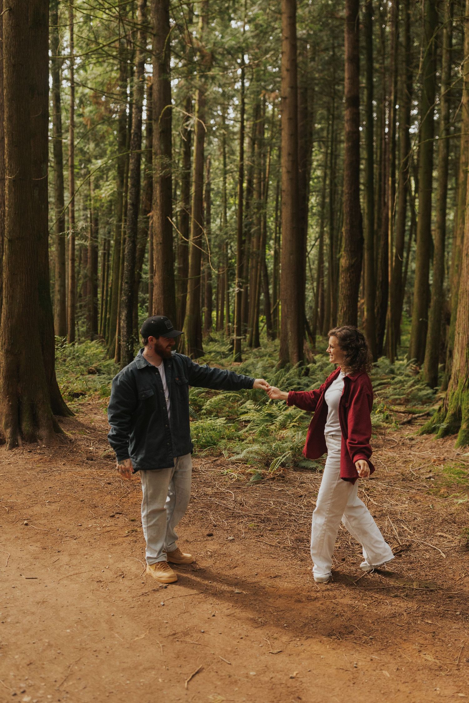 Two people walking and dancing together on a winding forest path.