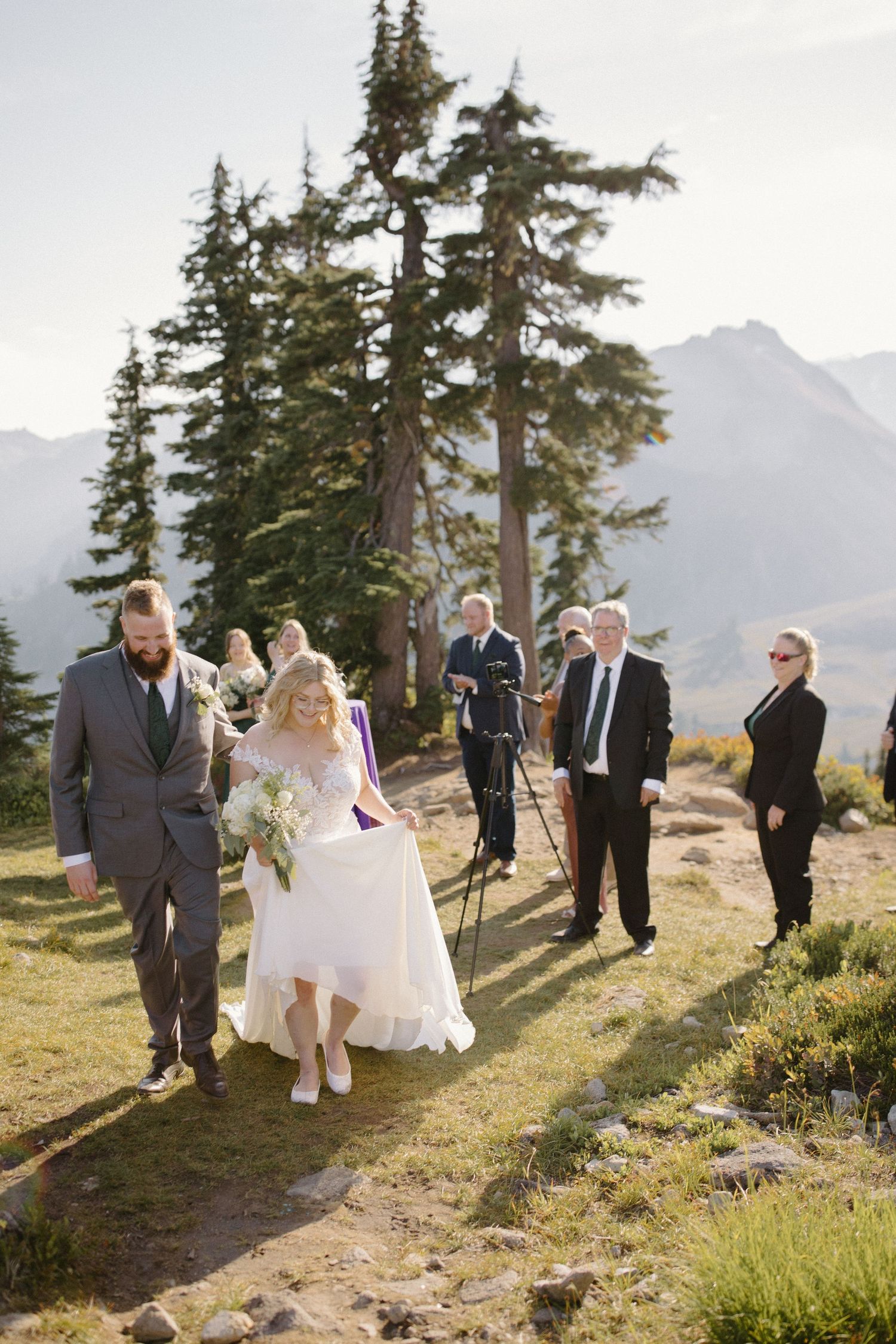 Wedding party walks along a mountain trail after the ceremony with scenic views.