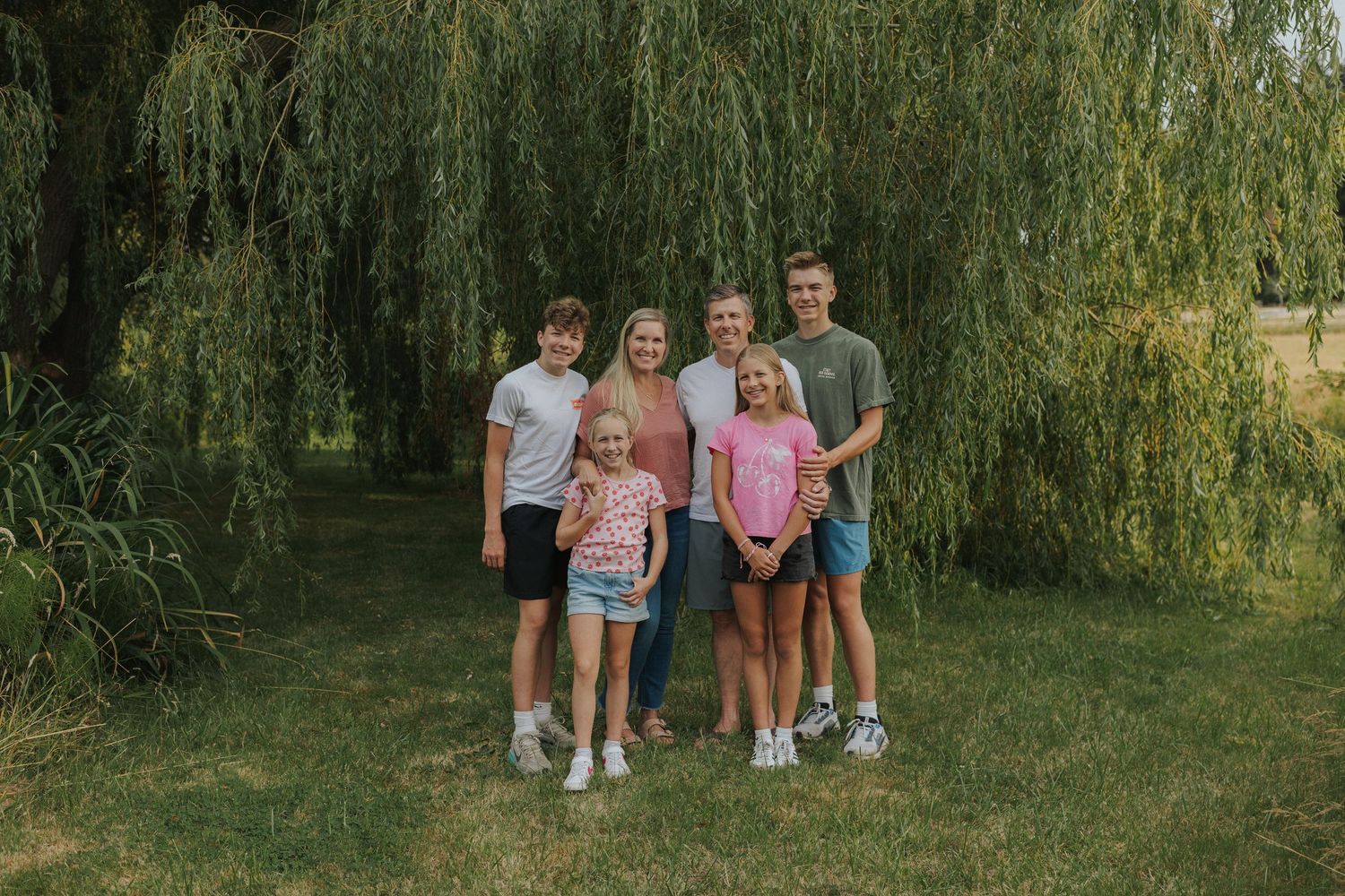 Group photo under weeping willow trees on summer day.