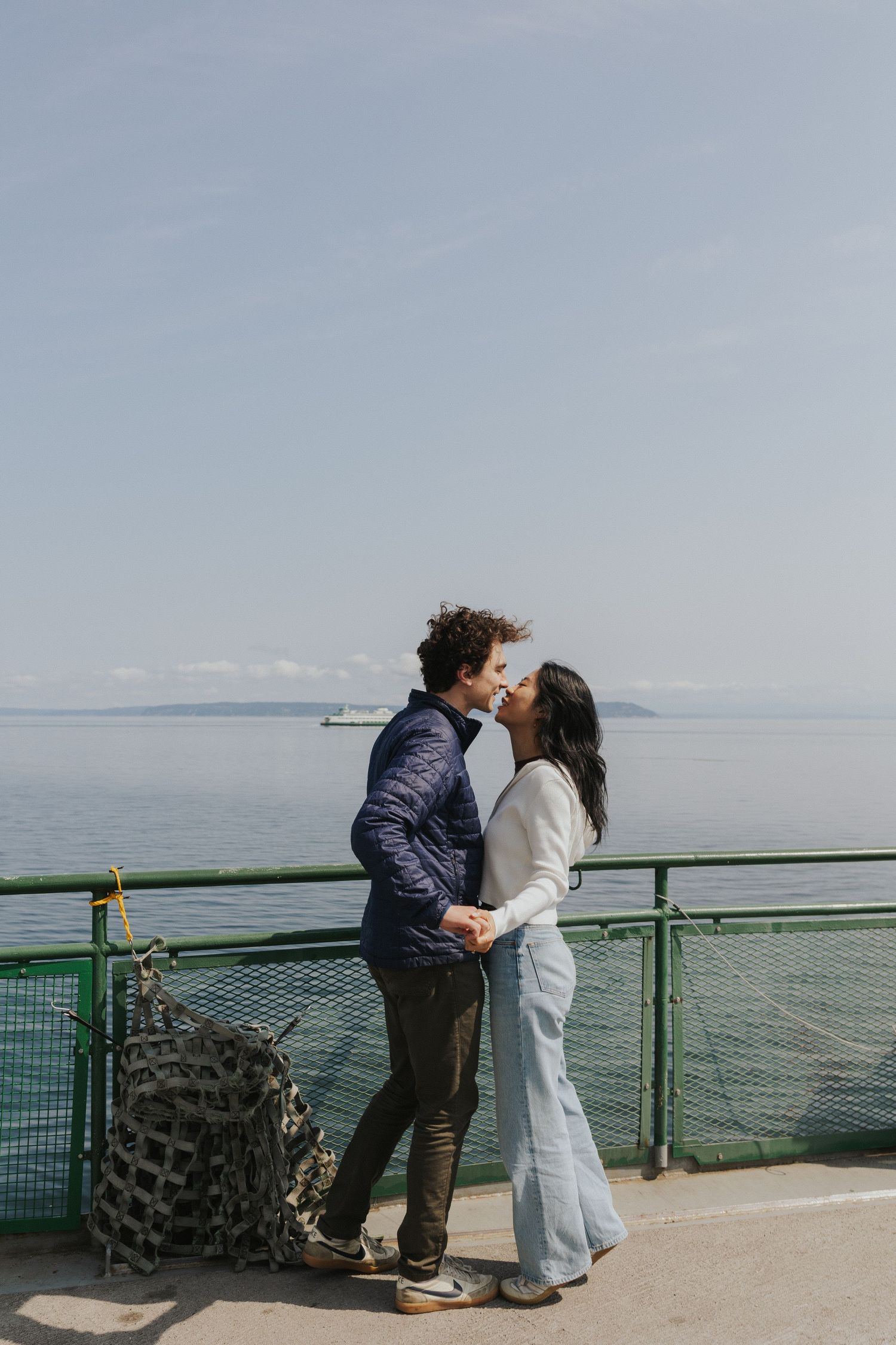 Romantic dance sequence on a ferry deck with green railings and ocean views.