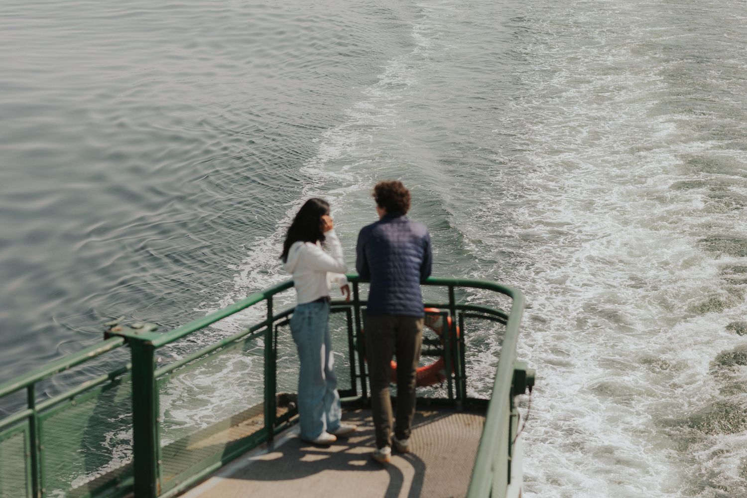 Couple looking out over the ferry's wake from the rear observation deck.