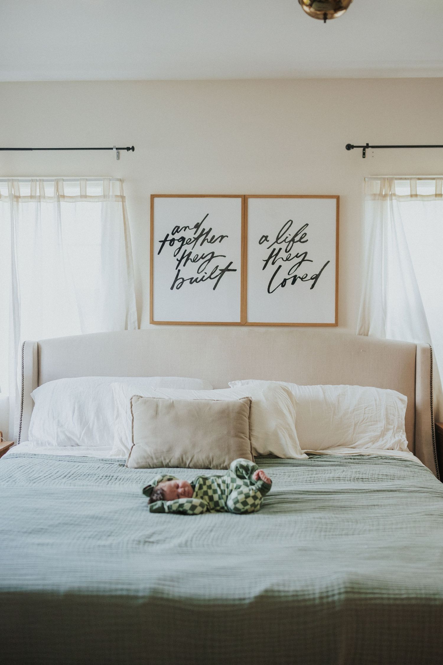 Serene bedroom interior with white bedding, calligraphy artwork, and natural light.