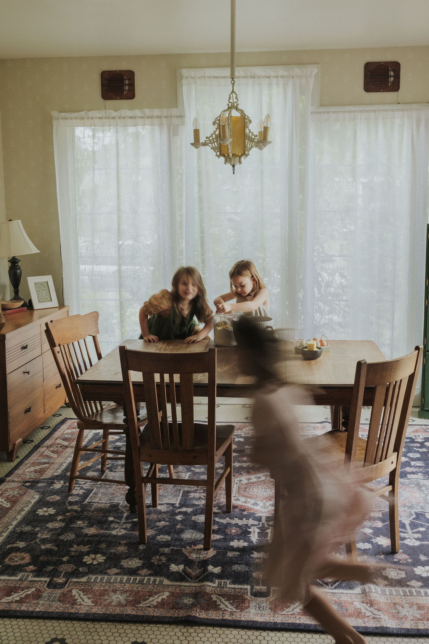 Motion blur sequence of someone running and jumping through a dining room with wooden furniture.
