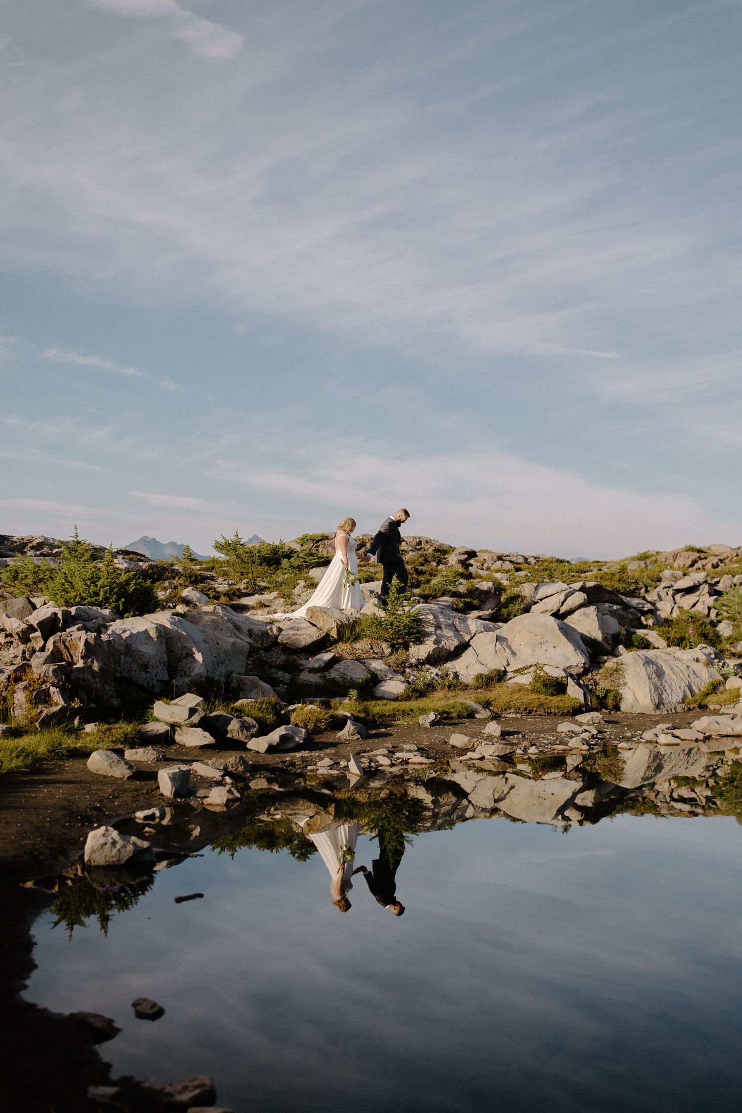 Scenic mountain lake reflects sky and rocks during outdoor wedding shoot.