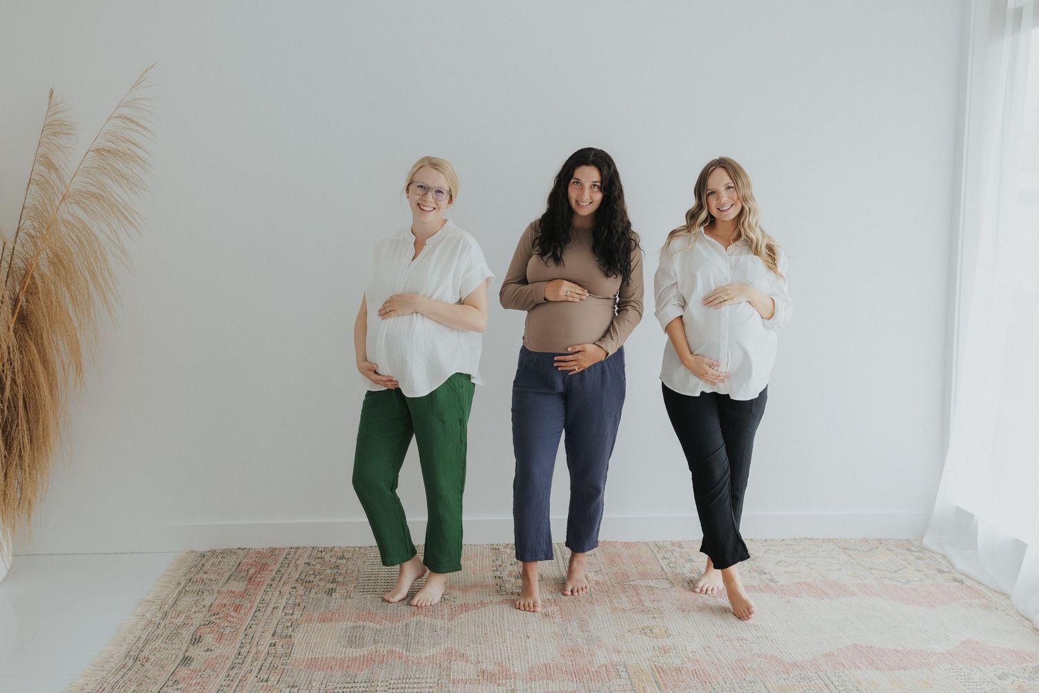 Group of people in casual attire standing against a white wall in a studio setting.