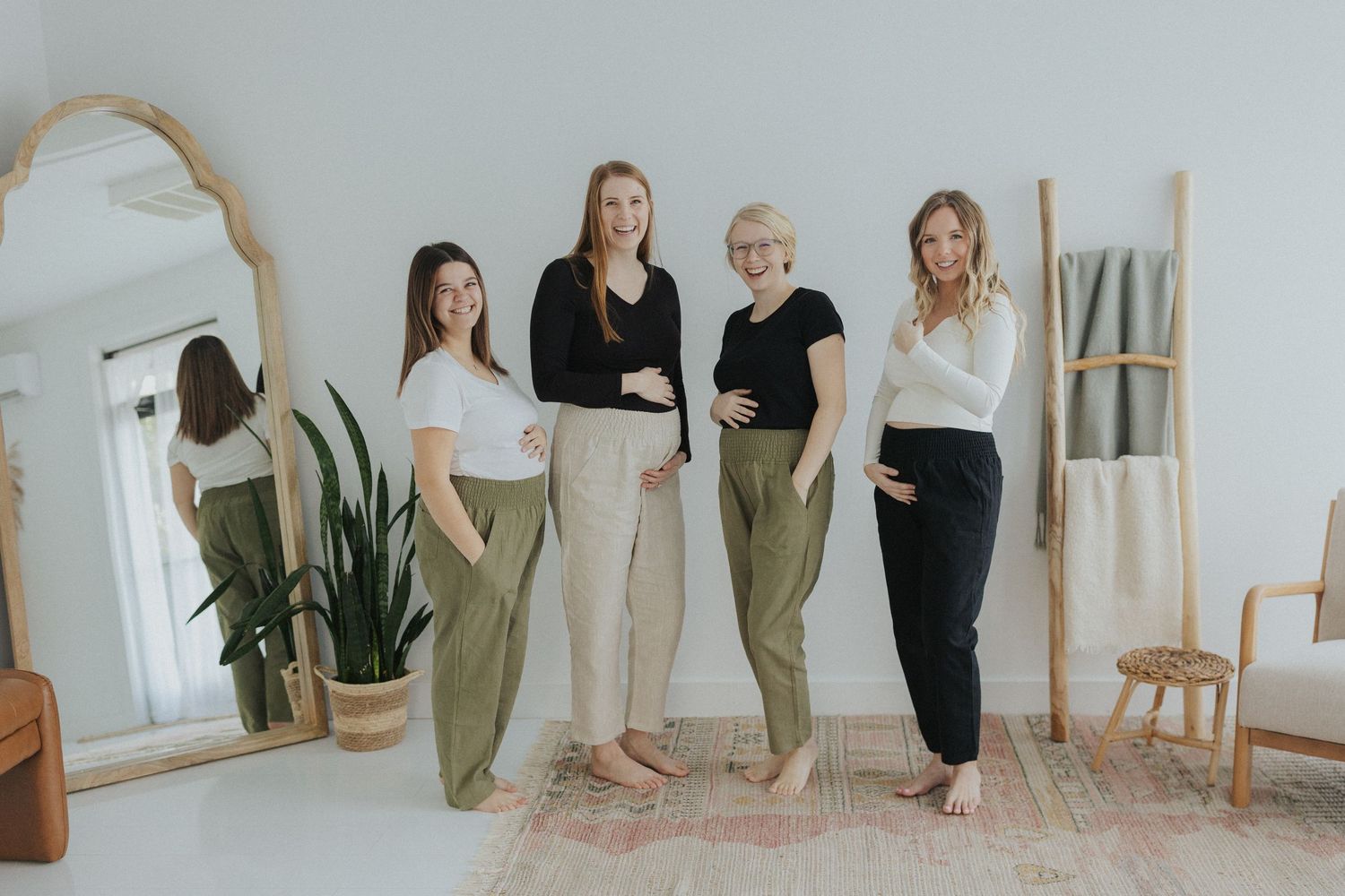 Group of people in casual wear posing together in minimalist white studio space.