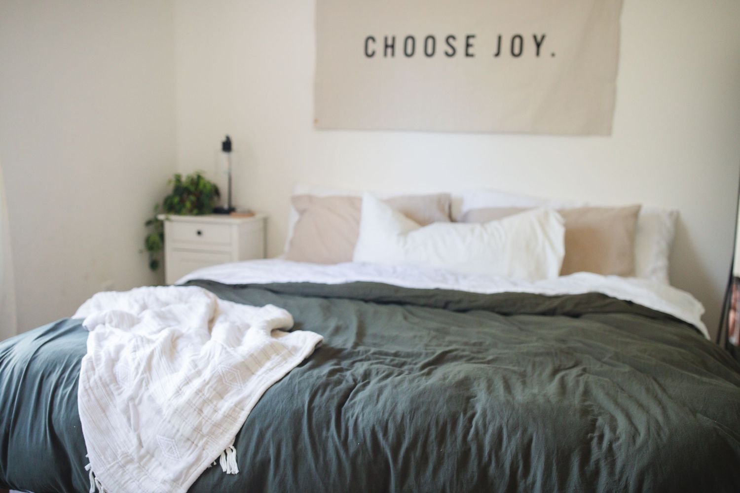 A clean white mattress with green bedding displayed in a minimalist bedroom setting.