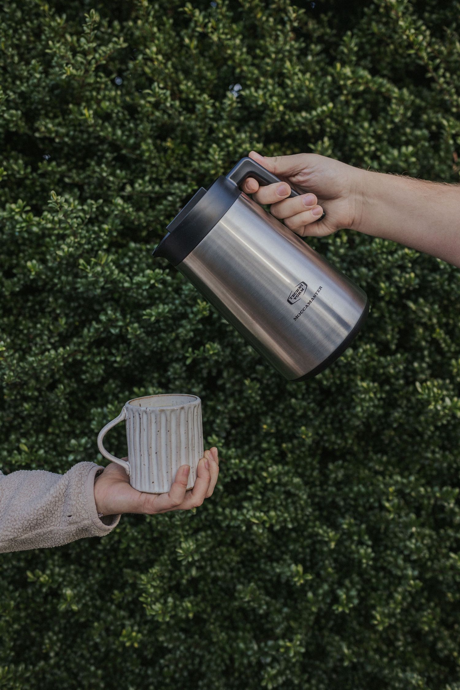 Multiple angles of hands pouring coffee from thermos into ceramic mug outdoors.