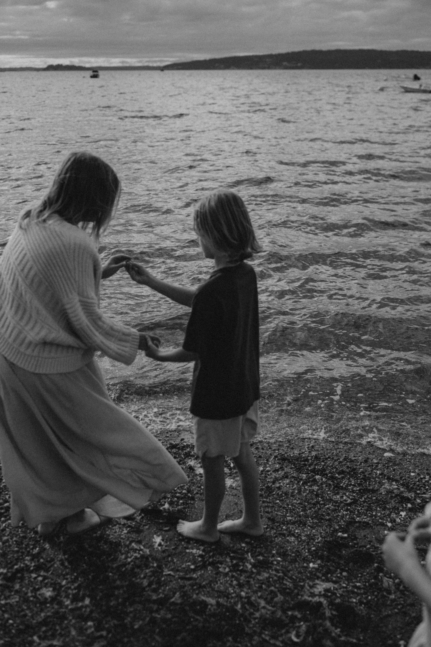 Black and white photos of family members walking along a rocky beach shoreline at sunset.