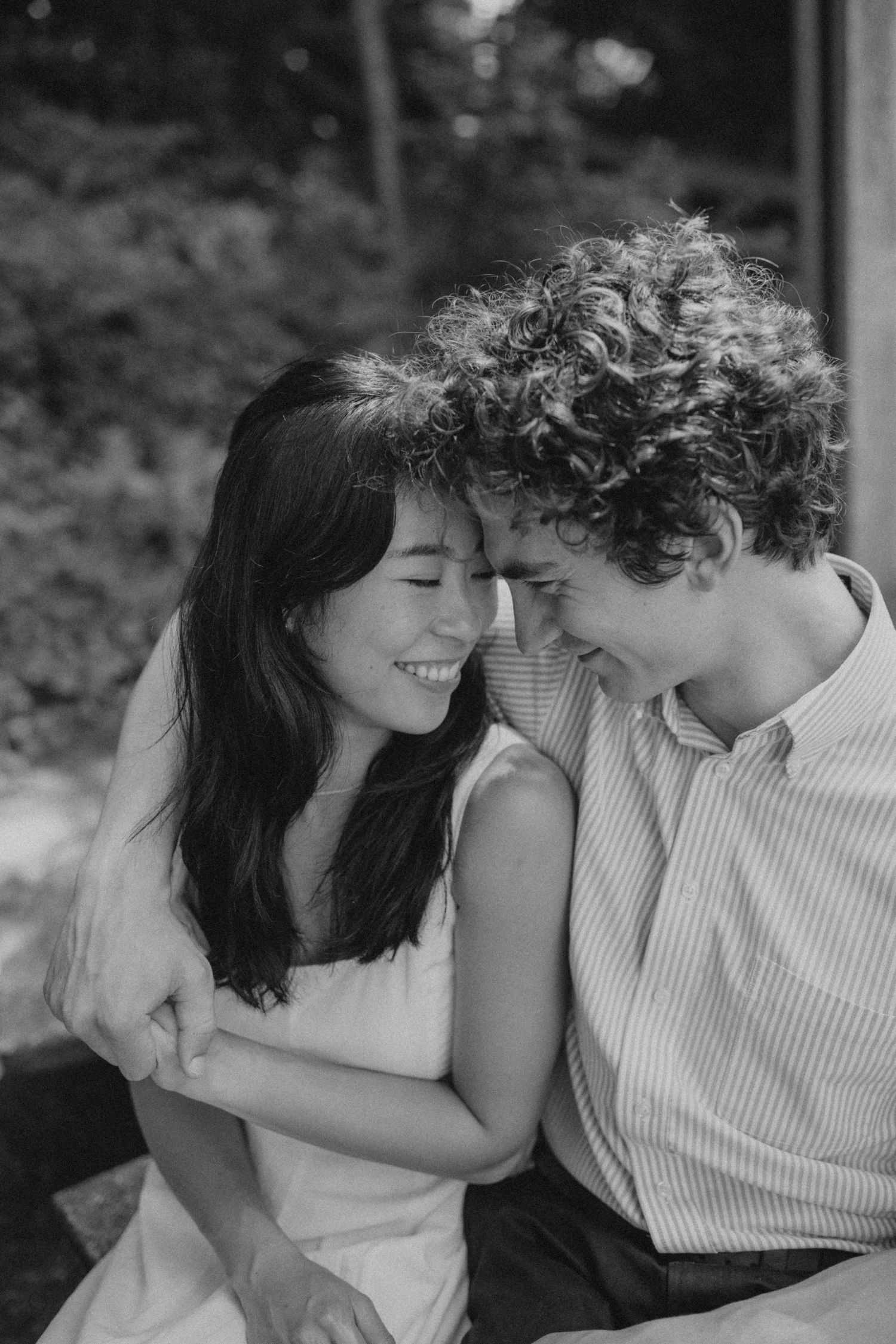 Intimate black and white portrait of a couple sharing a tender moment outdoors.