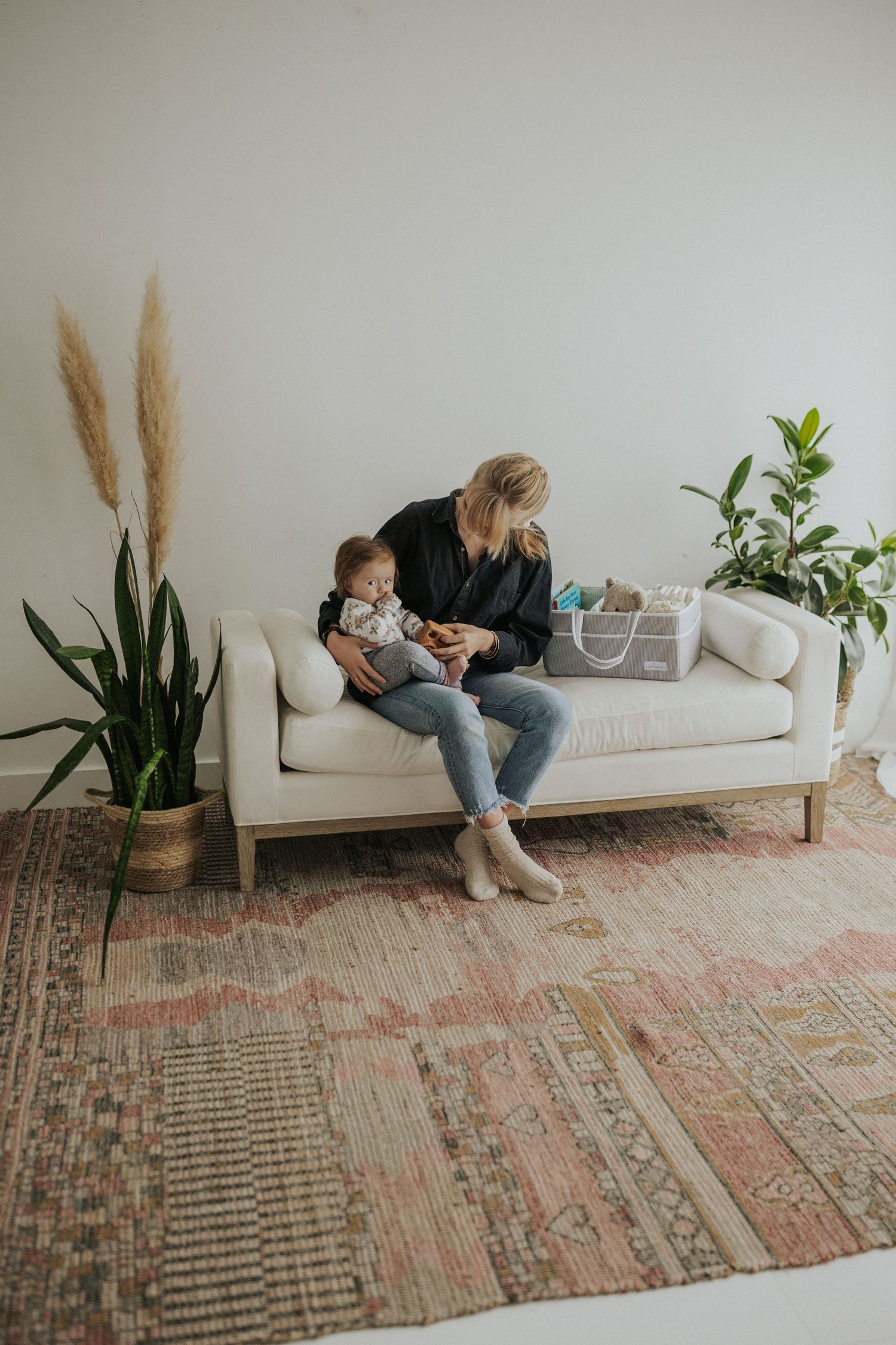 A cozy living room setting with white couch, pampas grass, and vintage pink rug.