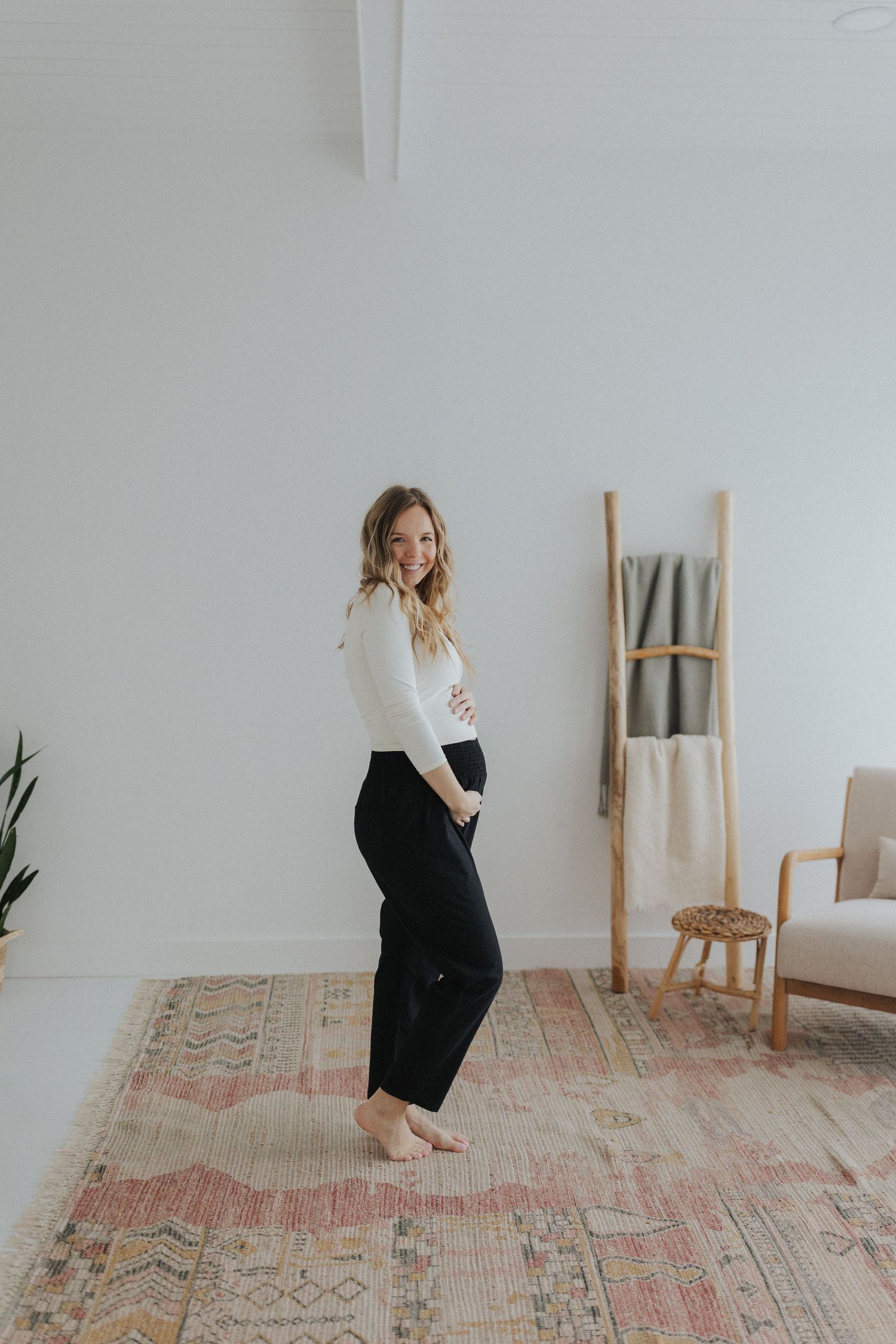 Person in black and white outfit dancing in bright minimalist studio space.