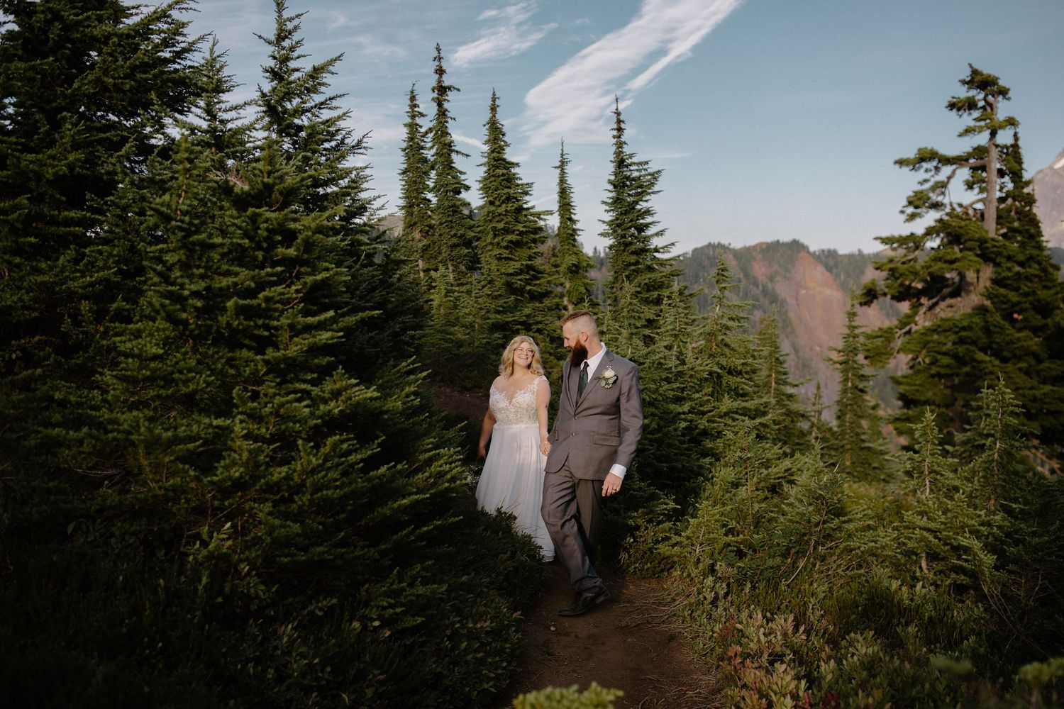 Mountain wedding photography among evergreen trees with dramatic peaks in background.