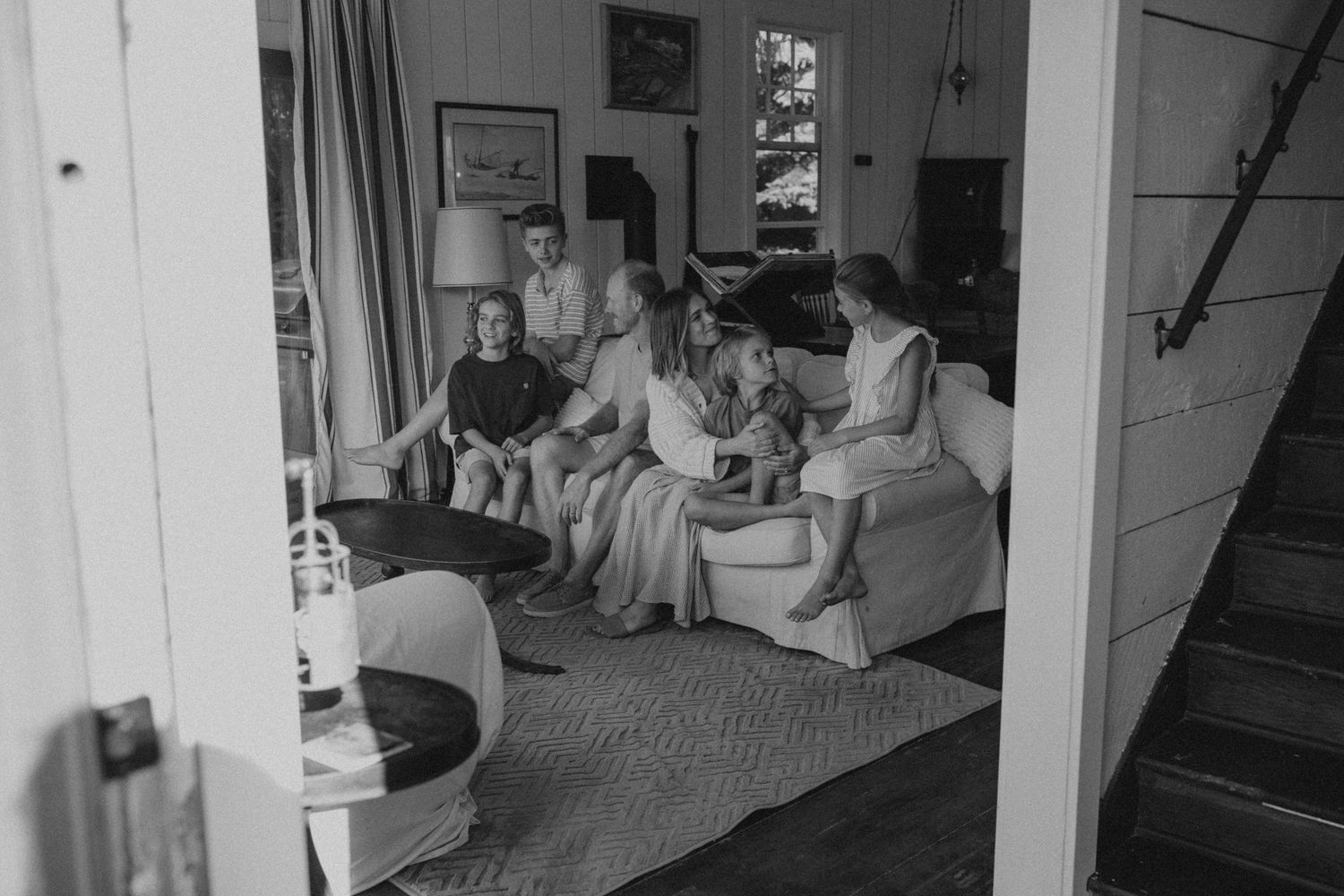 Black and white interior photo of family relaxing in casual home setting.