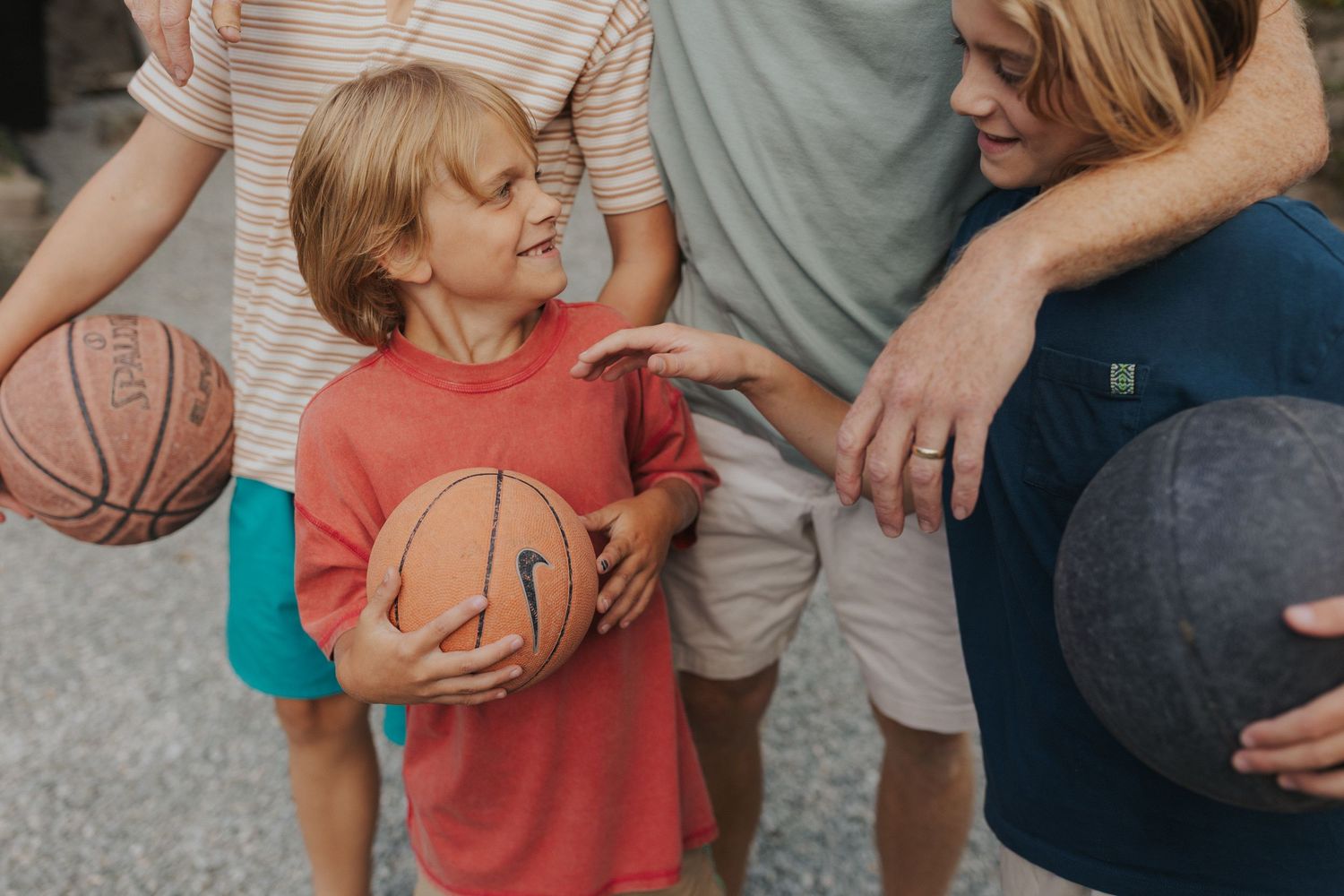 Family playing with a basketball together outdoors on a sunny day.