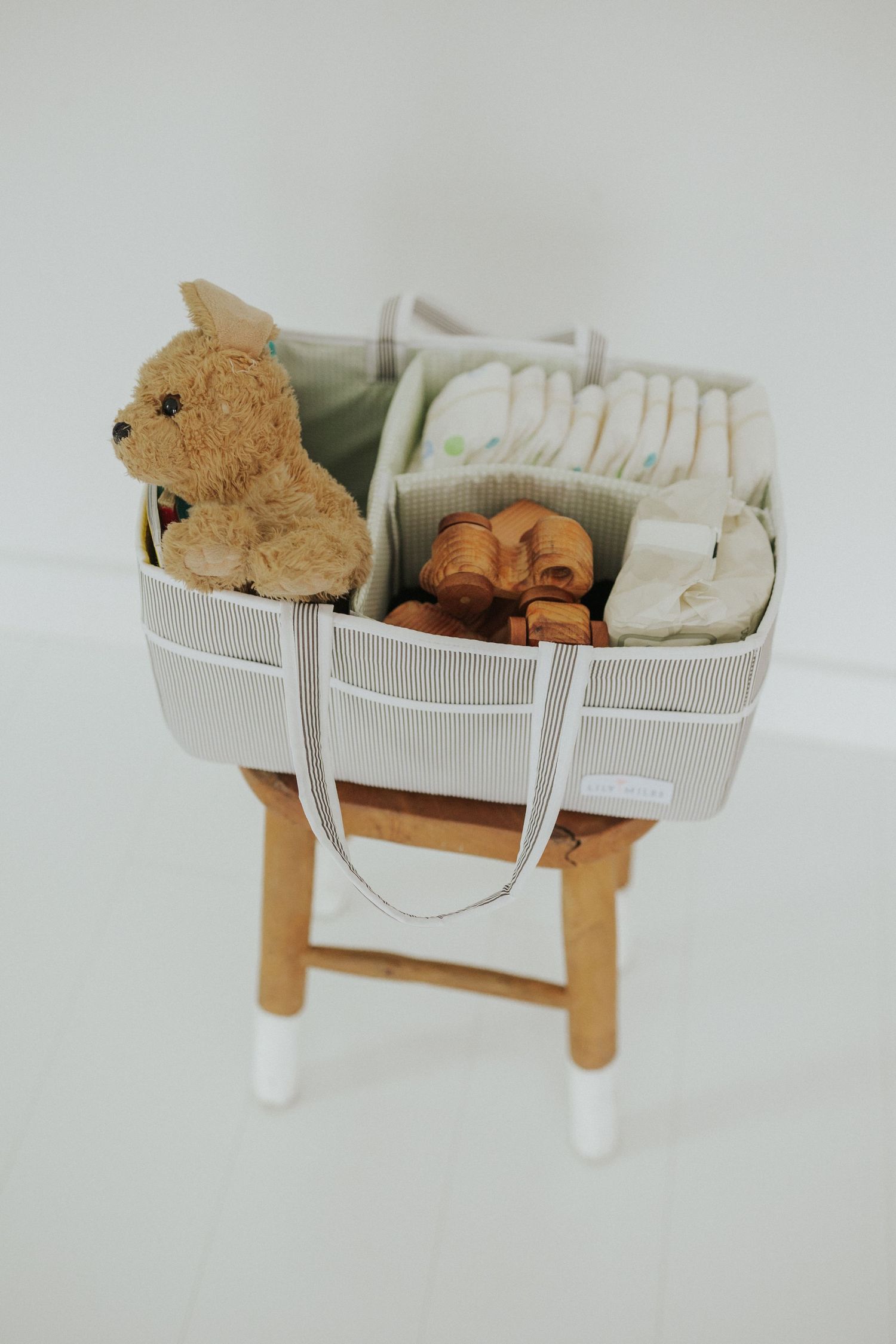 Multiple angles of a gray storage basket with wooden legs holding toys and plush items.
