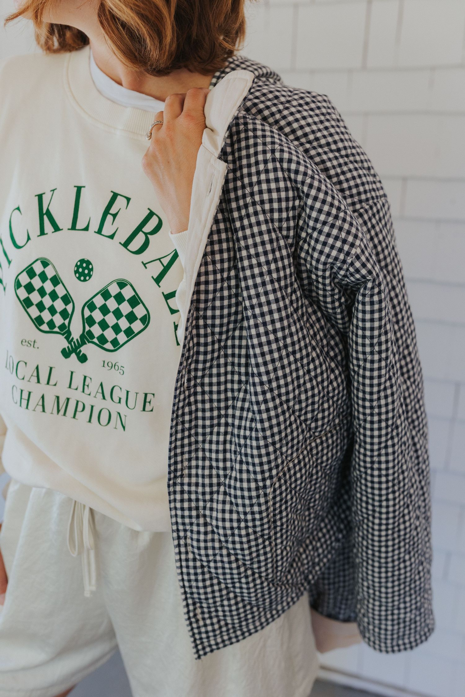 Close-up of gingham and white sweatshirts with green Pickleball Champion text design.