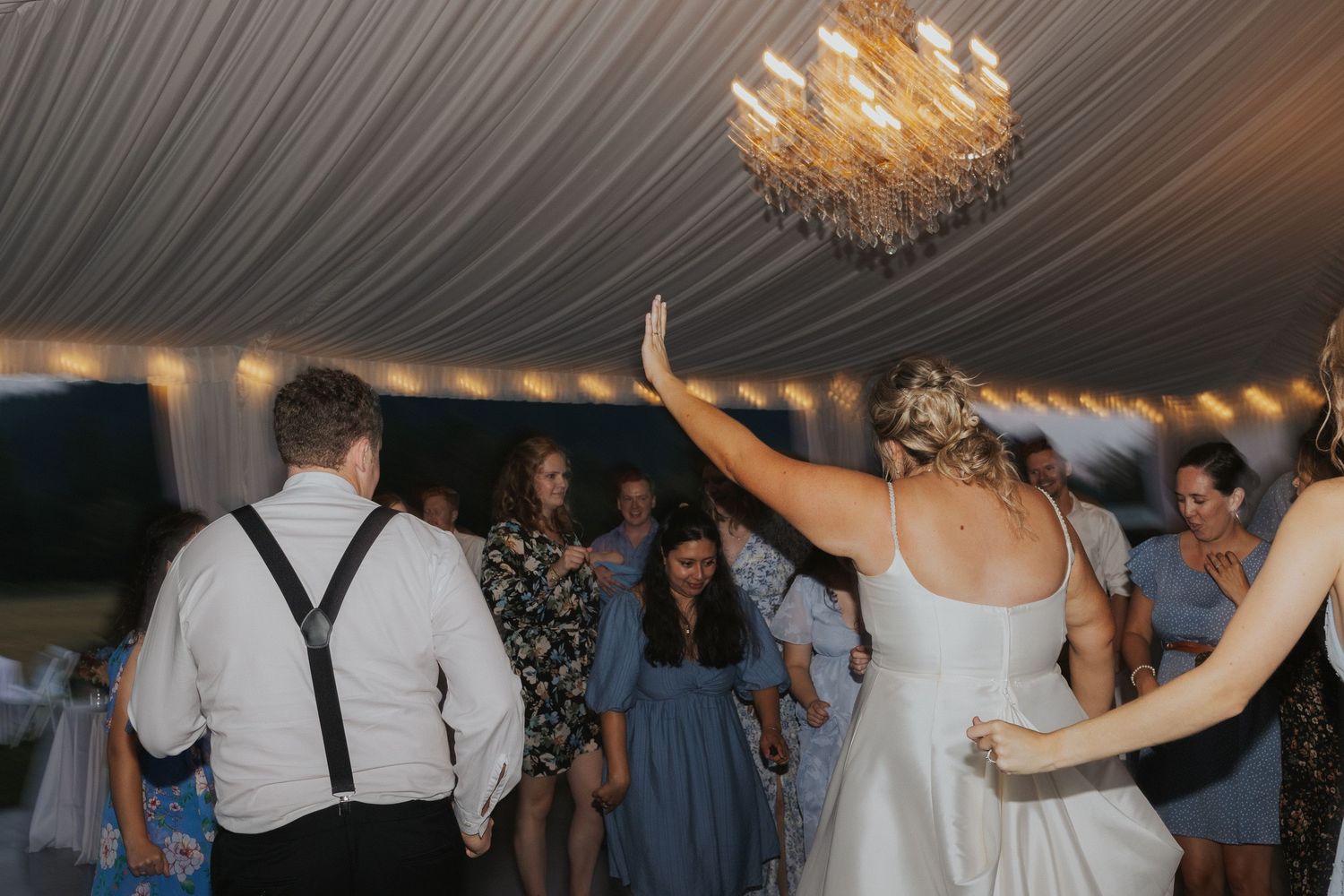 Wedding guests dancing and celebrating under warm indoor lighting.