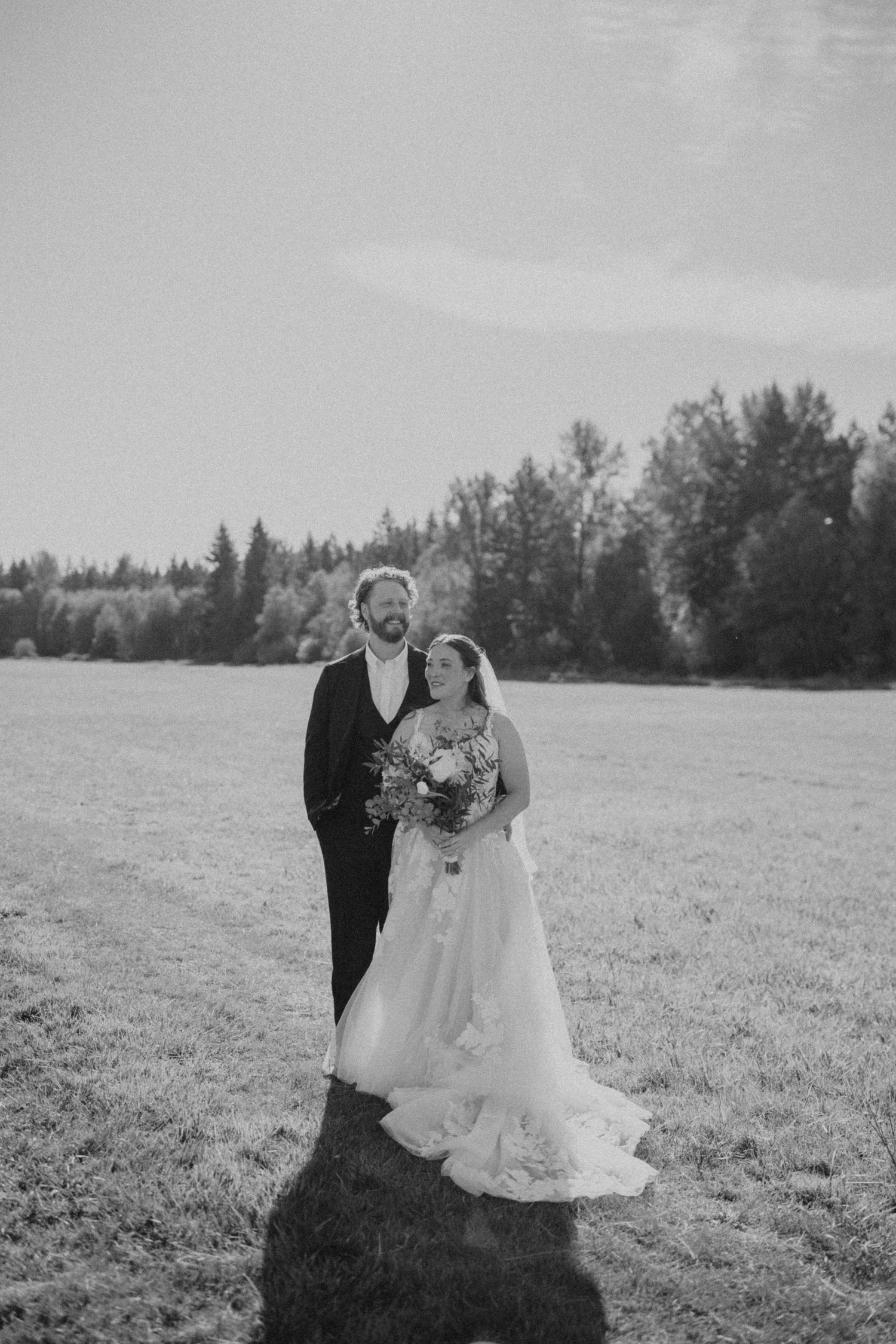 Black and white wedding photos showing a couple in an open field with trees in the background.