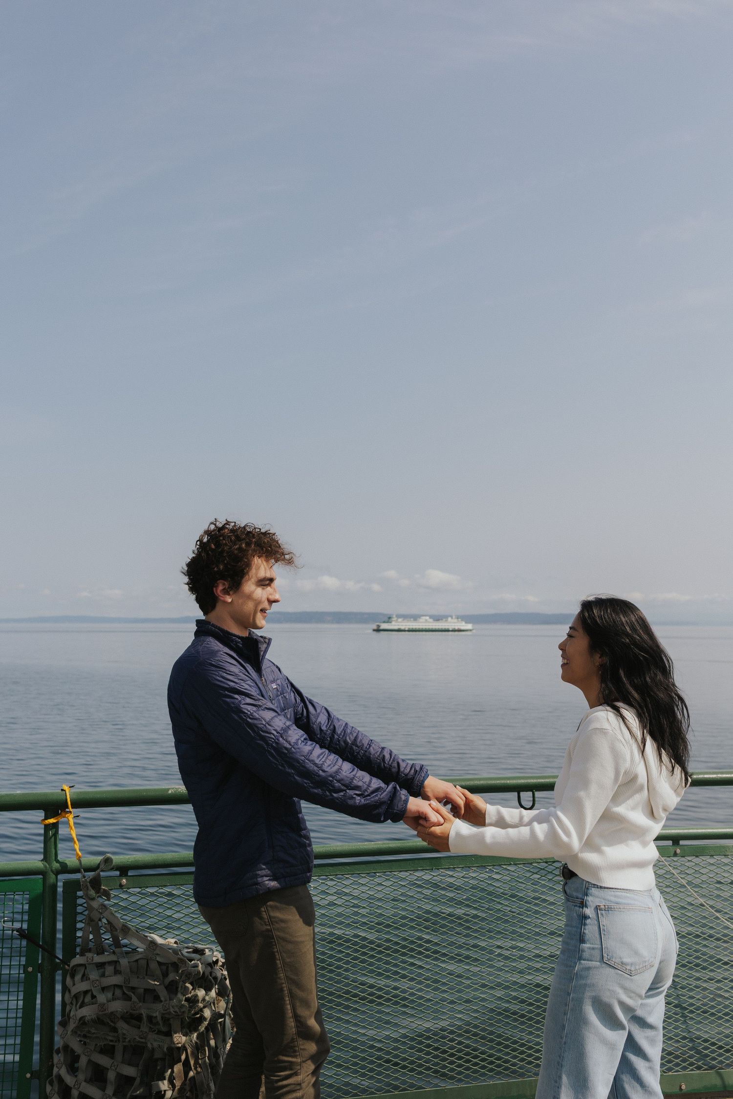 Two people dancing together on a ferry deck with ocean views in the background.