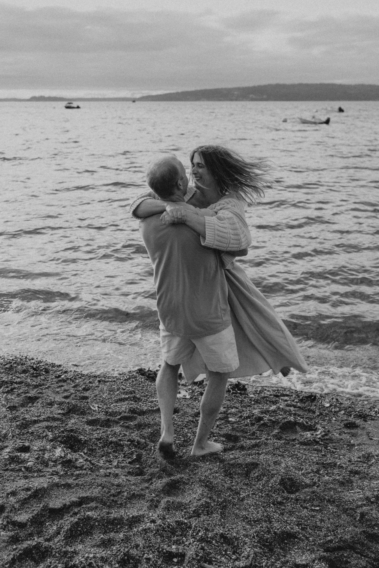 Black and white photo of intimate moment shared on rocky shoreline.