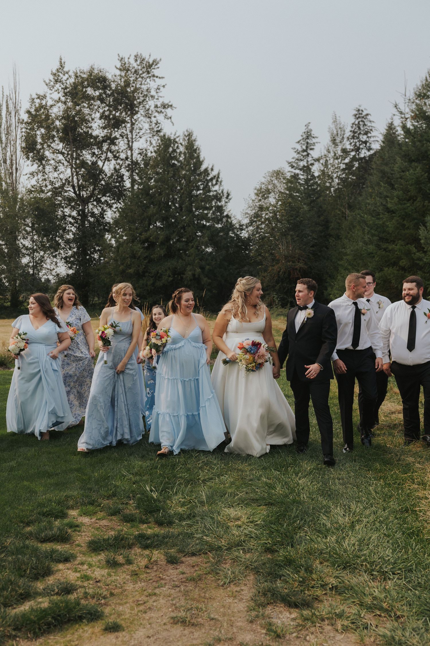 Bridesmaids in powder blue dresses and groomsmen in dark suits line up for a wedding photo.