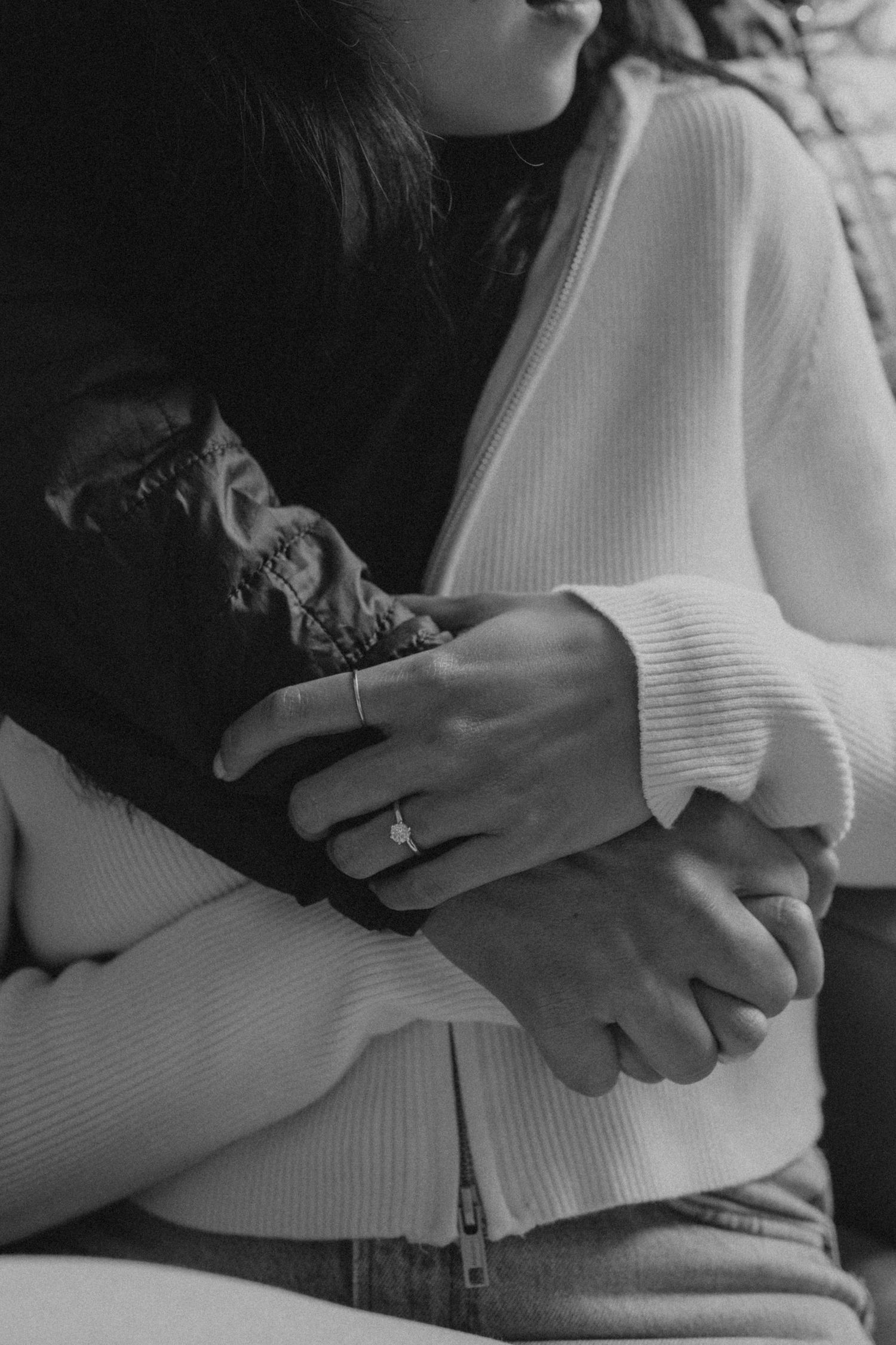 Black and white close-up of hands embracing in tender moment.