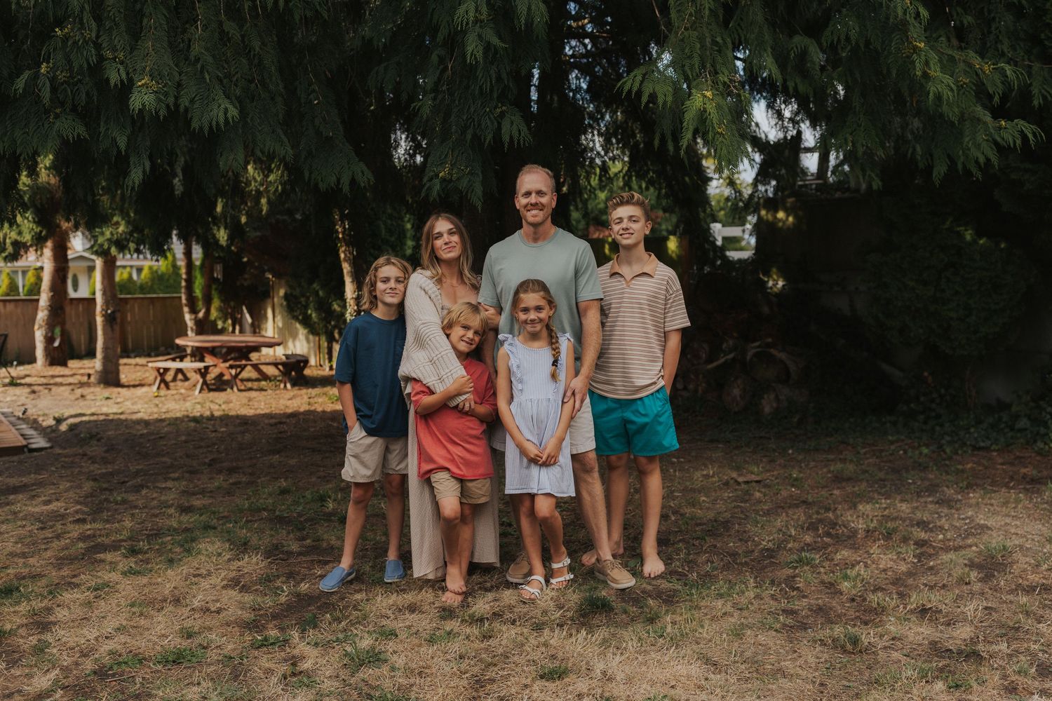 Group standing together outdoors under trees on a sunny afternoon.