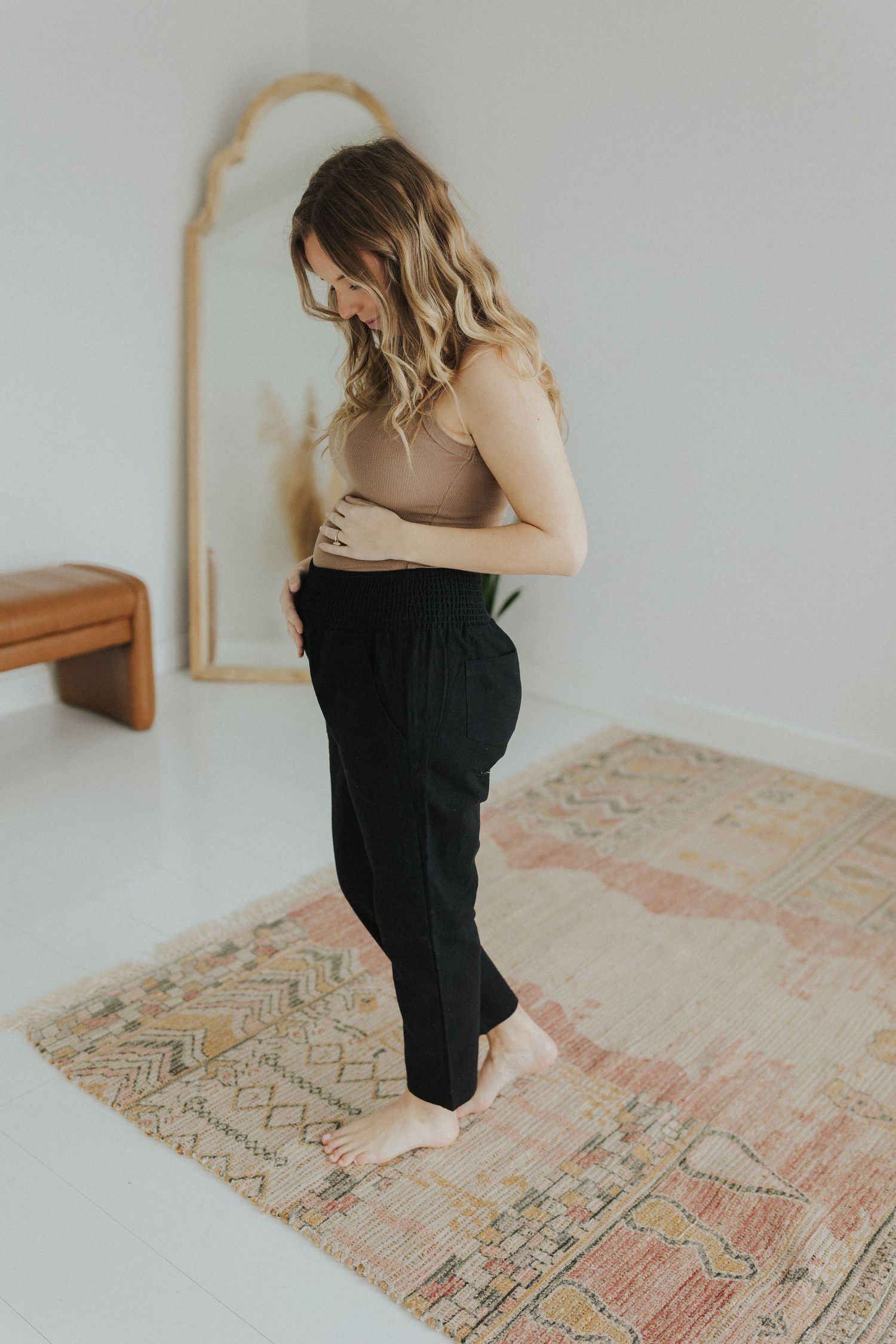 Person in black dress kneeling on vintage patterned rug.