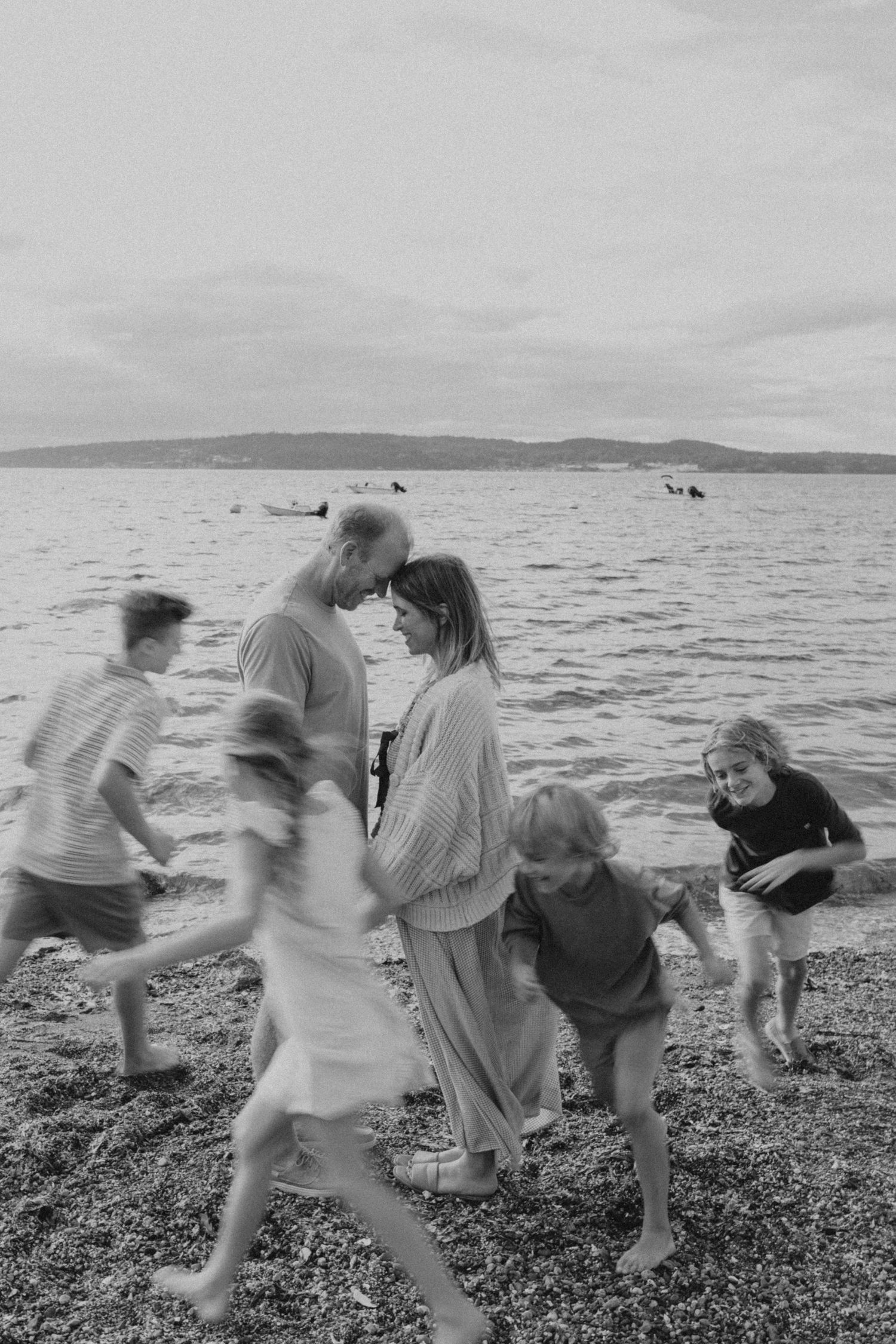 Black and white photo of children playing and running on a rocky beach.