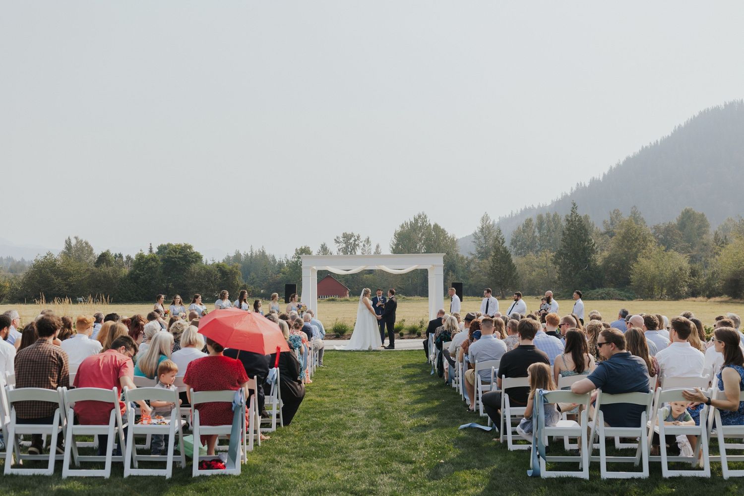 Rows of white chairs set up for an outdoor wedding ceremony with mountain views in the background.