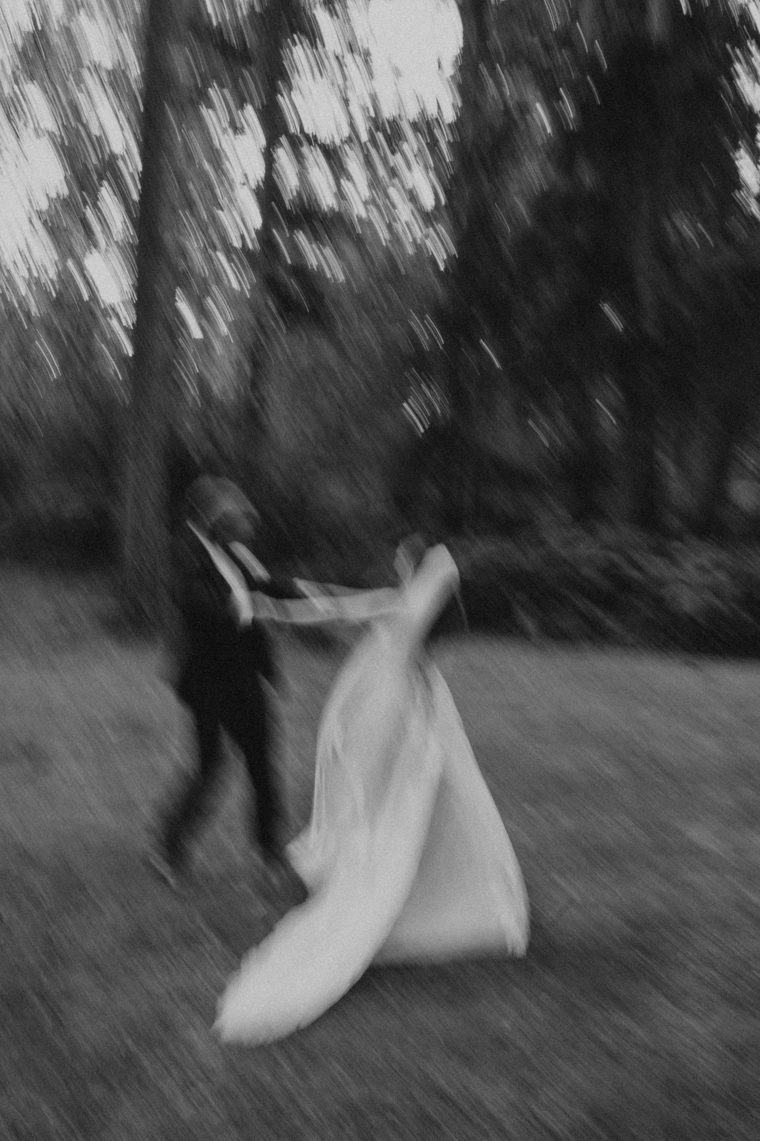 Artistic black and white photo of a dancing couple in a forest setting.