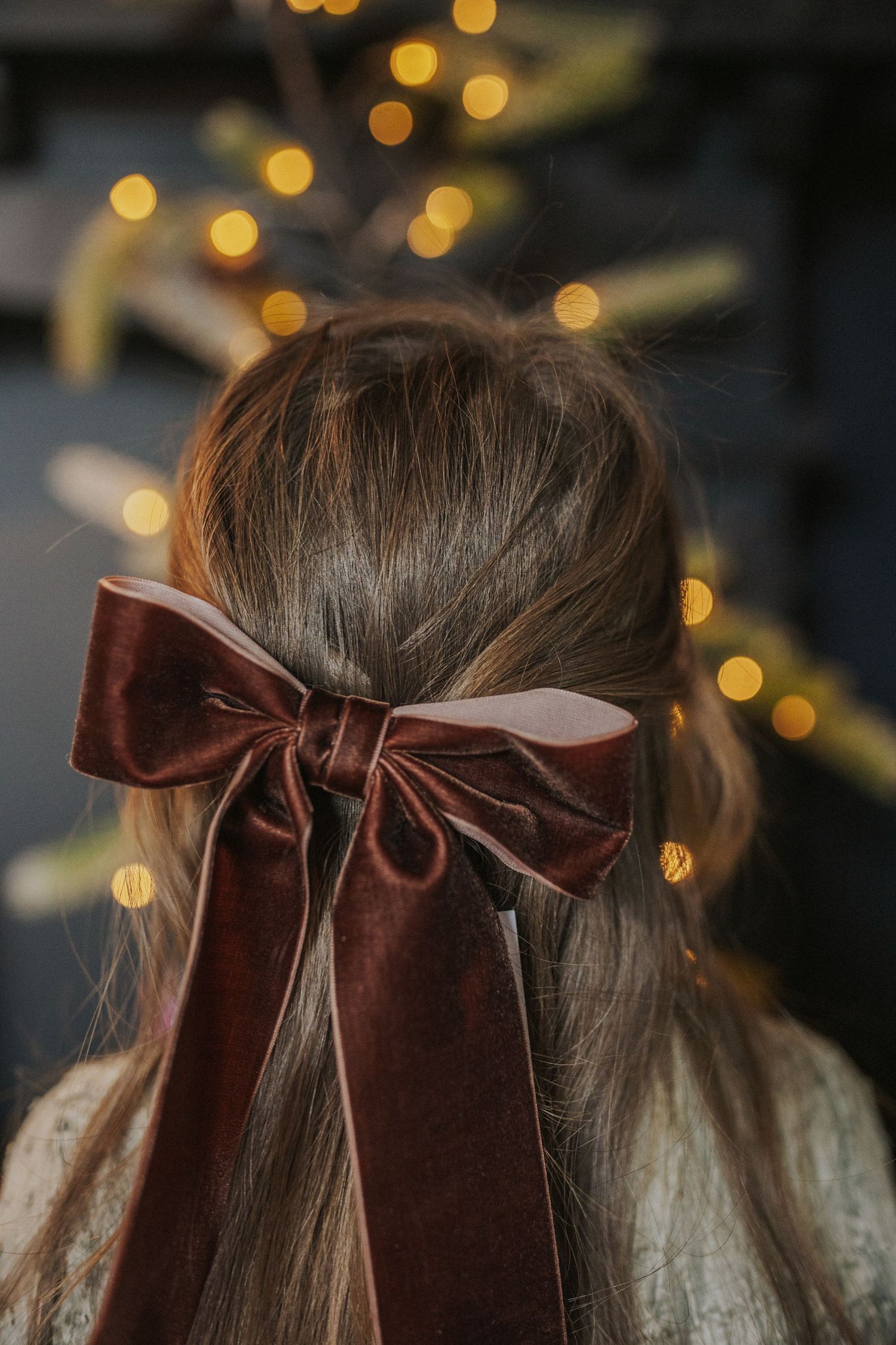 Close-up shots of velvet brown bows against blurred holiday lights.