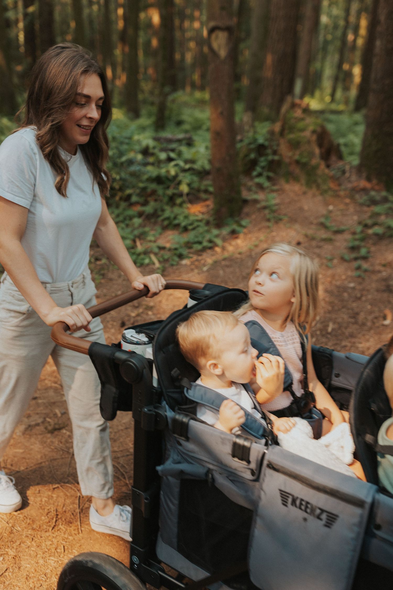 Children enjoying a ride in a black wagon on a forest trail.