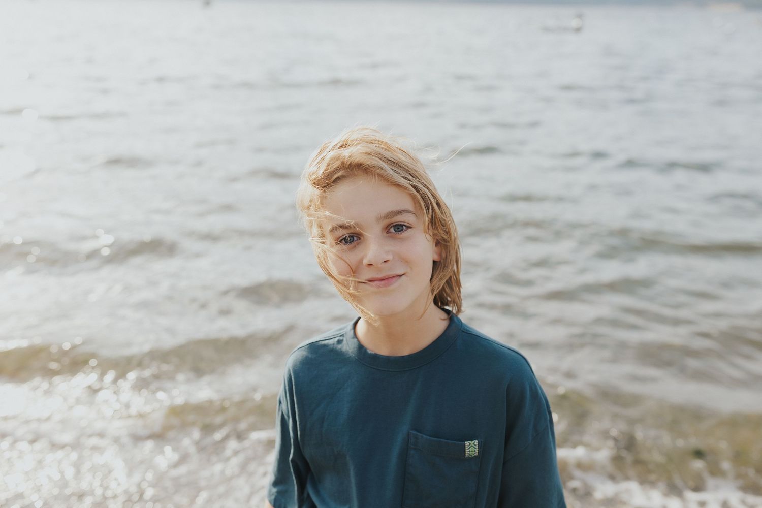 Candid seaside portrait showing joyful embrace and laughter against ocean backdrop.