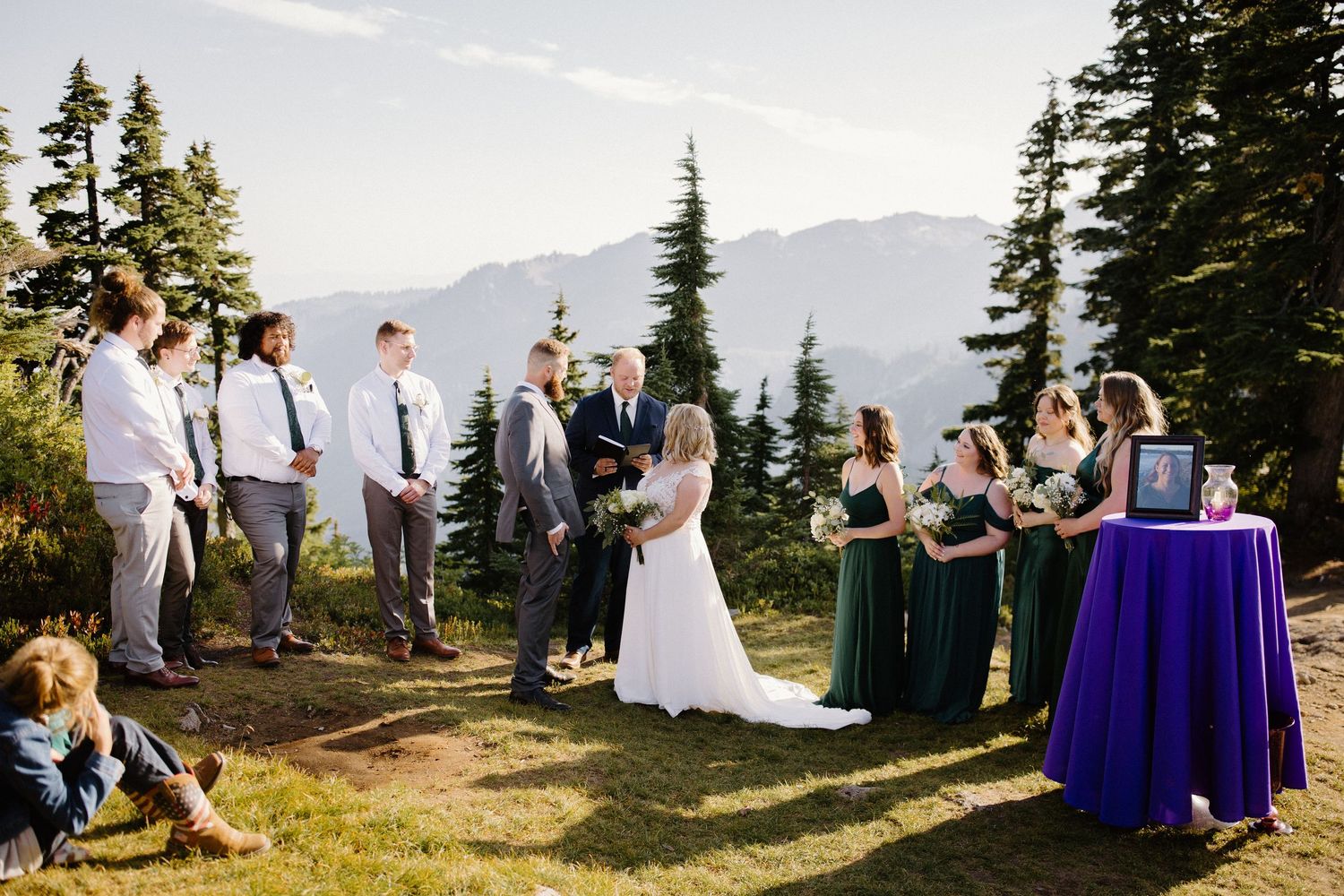 Wedding ceremony setup on mountain overlook with purple decor and mountain vista in background.