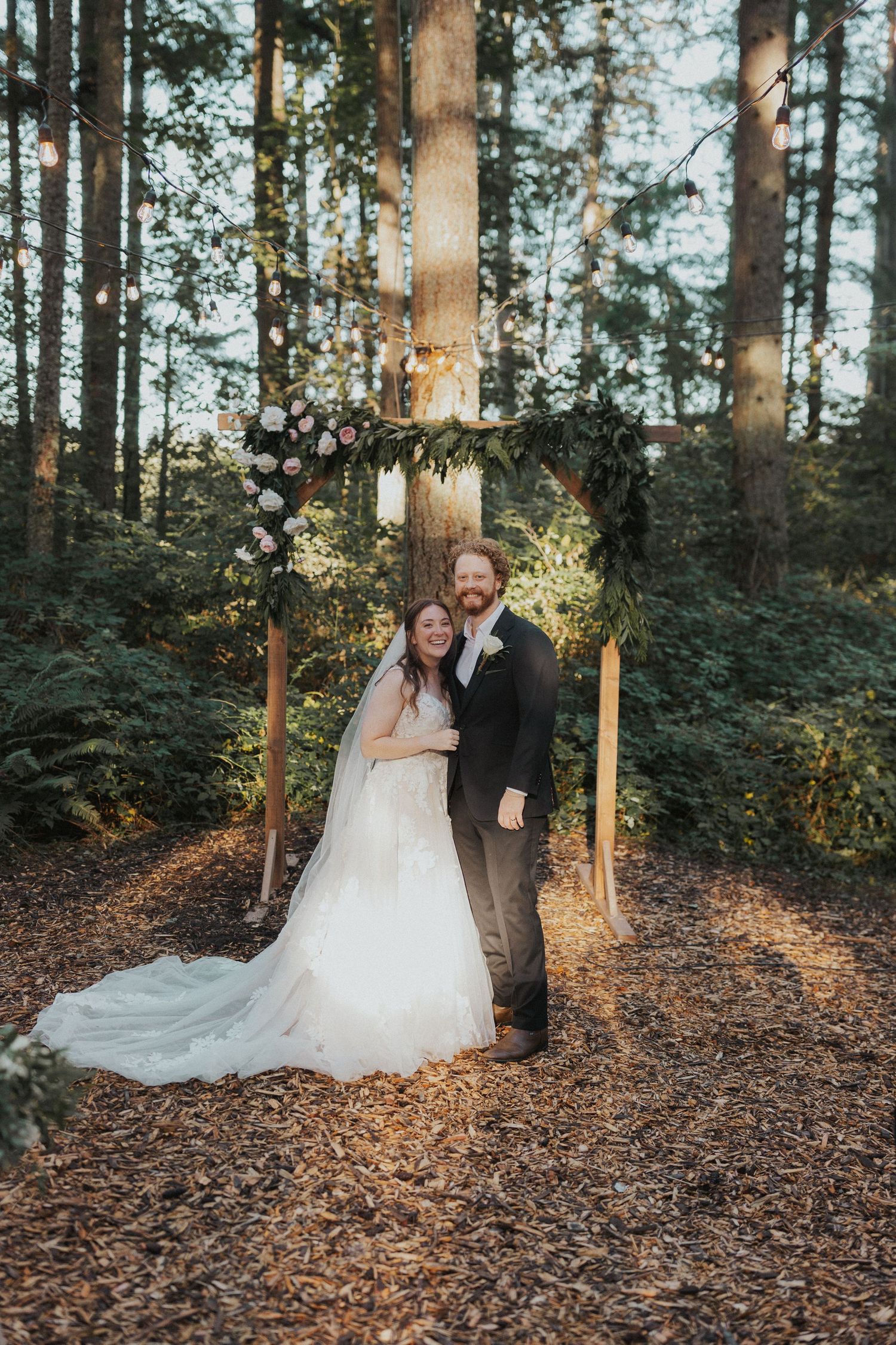A wedding couple shares an intimate moment in a sunlit forest setting.