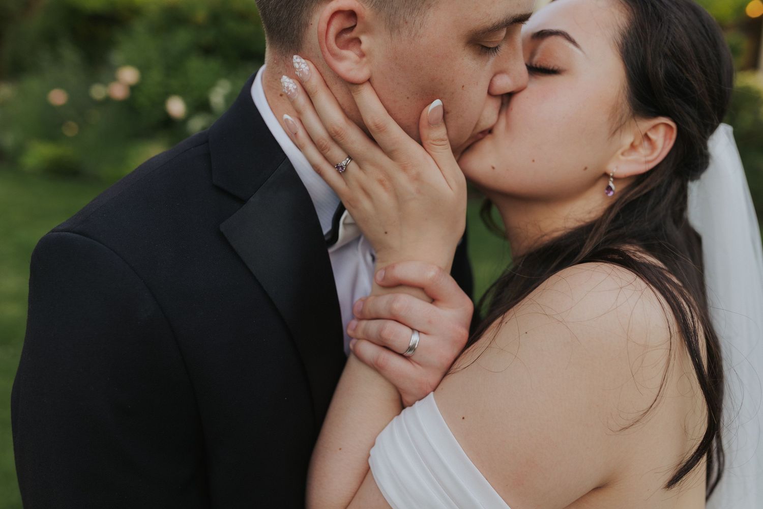 Romantic moment captured between newlyweds against a garden backdrop.