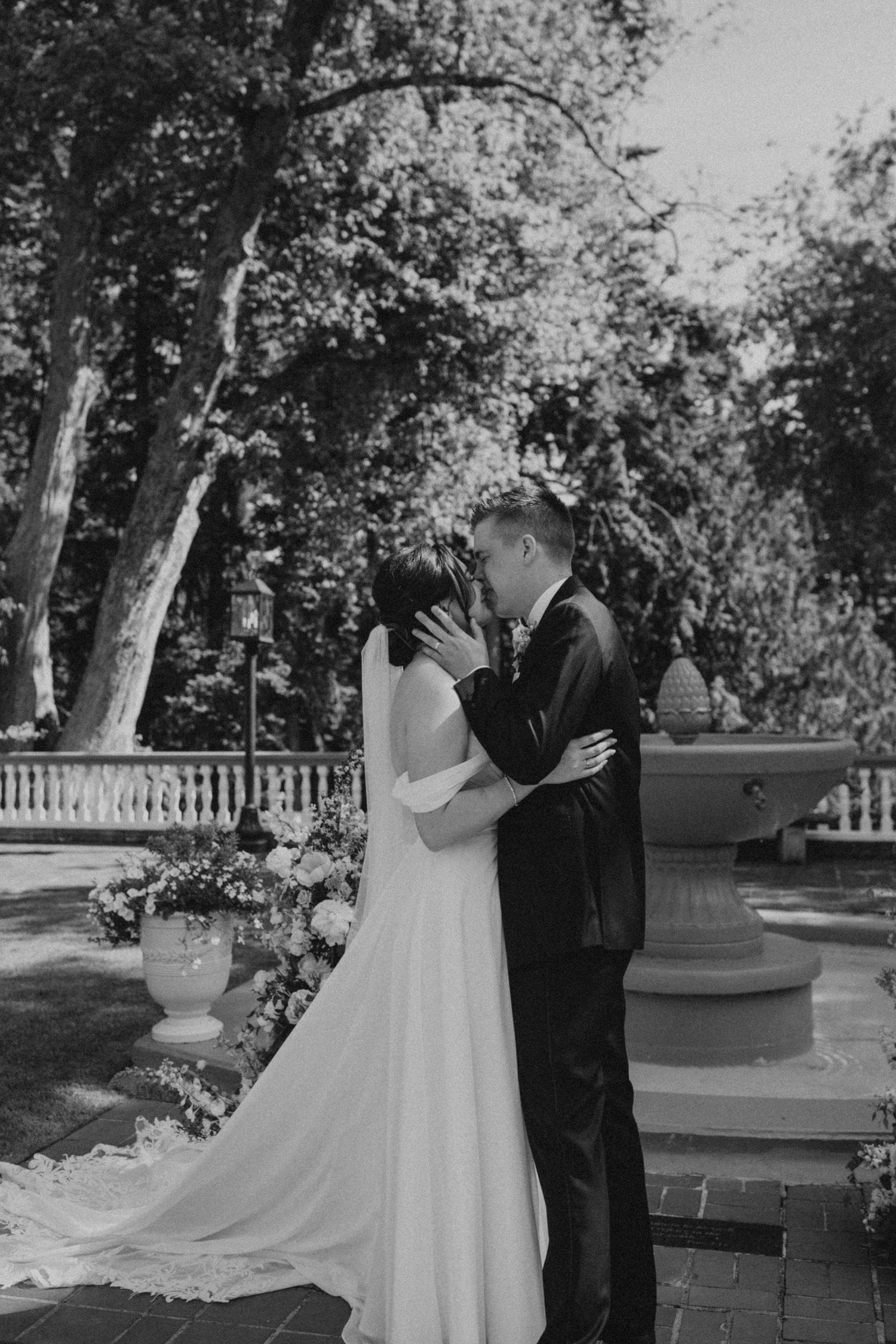 Black and white photo of wedding couple sharing a moment on brick patio.