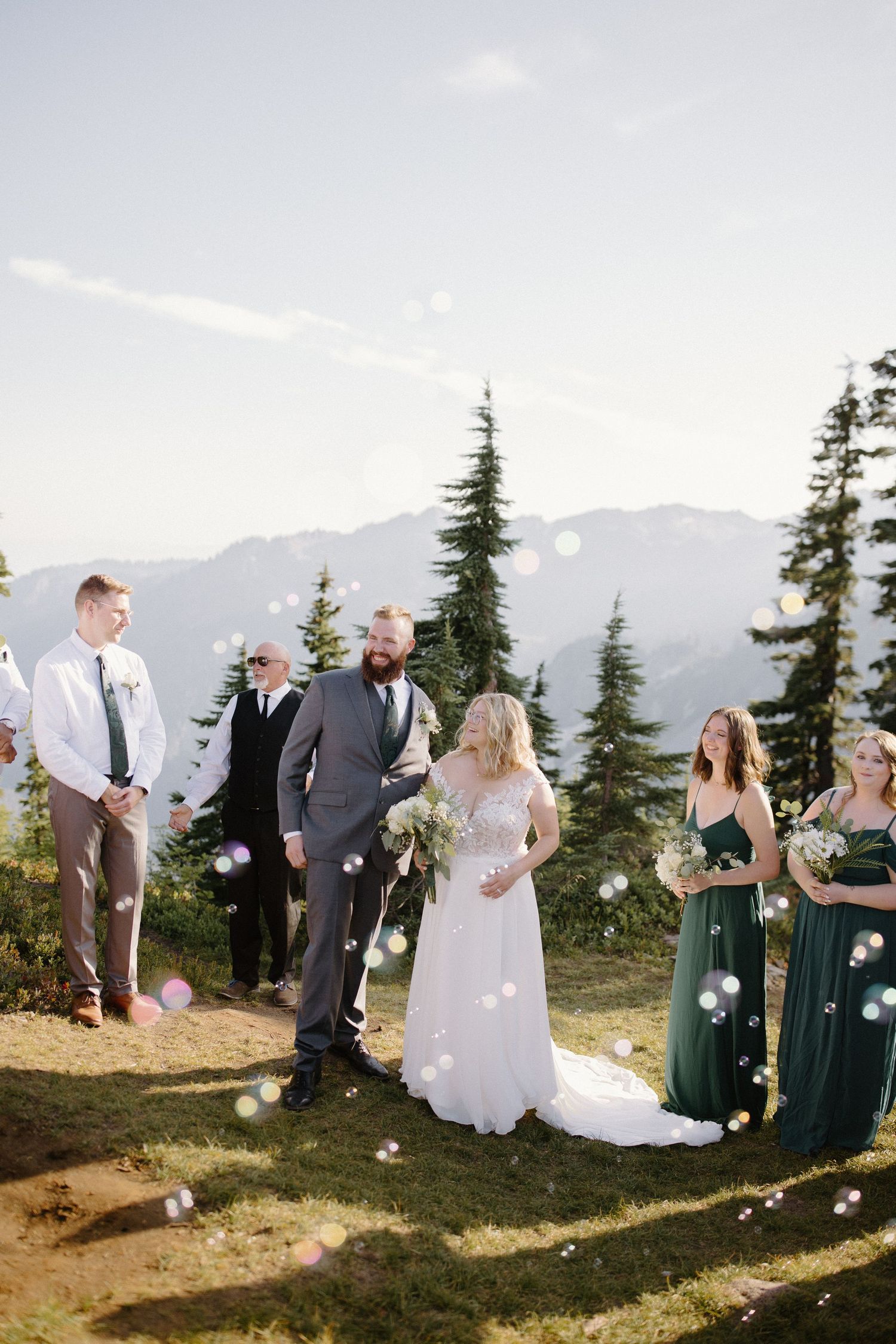 Wedding guests throw flower petals in celebration on a scenic mountain overlook.