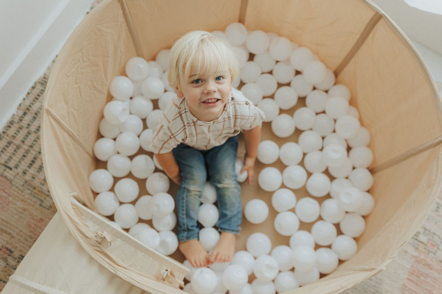 White ball pit filled with foam spheres in a cardboard box play area.