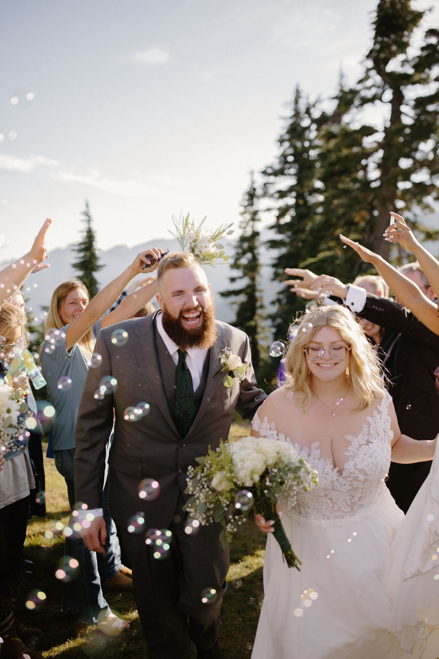 Joyful wedding party celebrates with confetti toss in mountain setting.