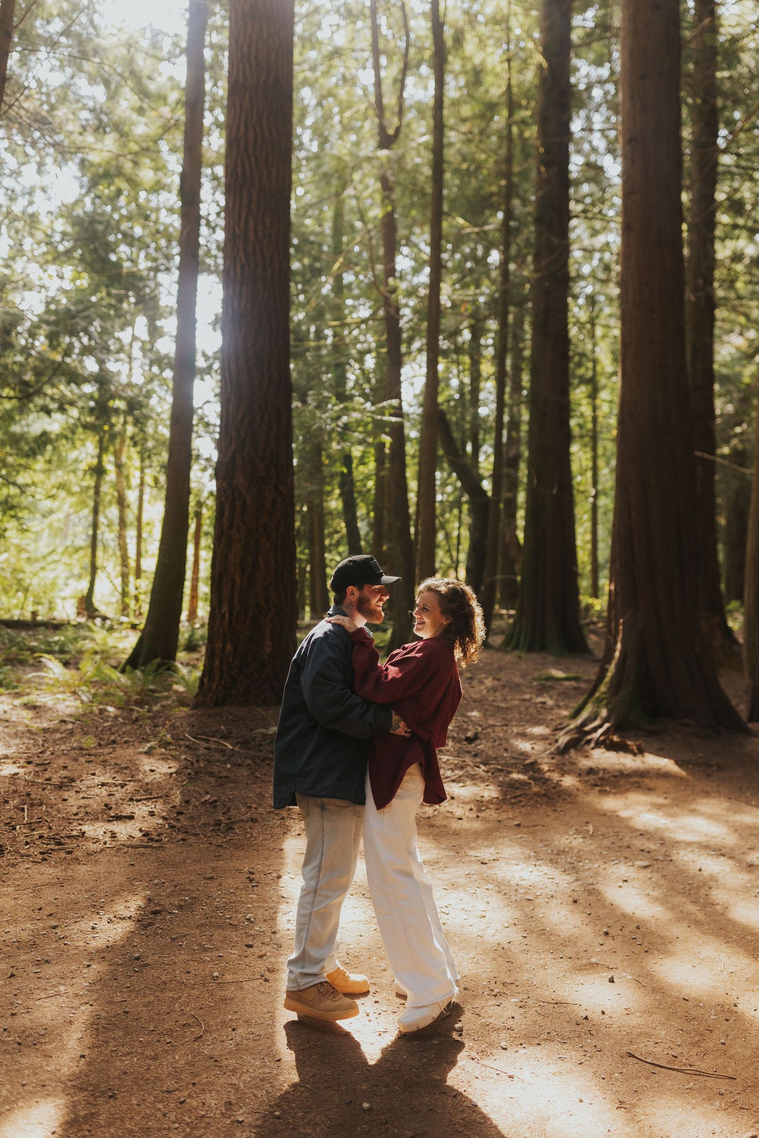 Sunbeams filter through forest trees as a couple dances in the golden light.
